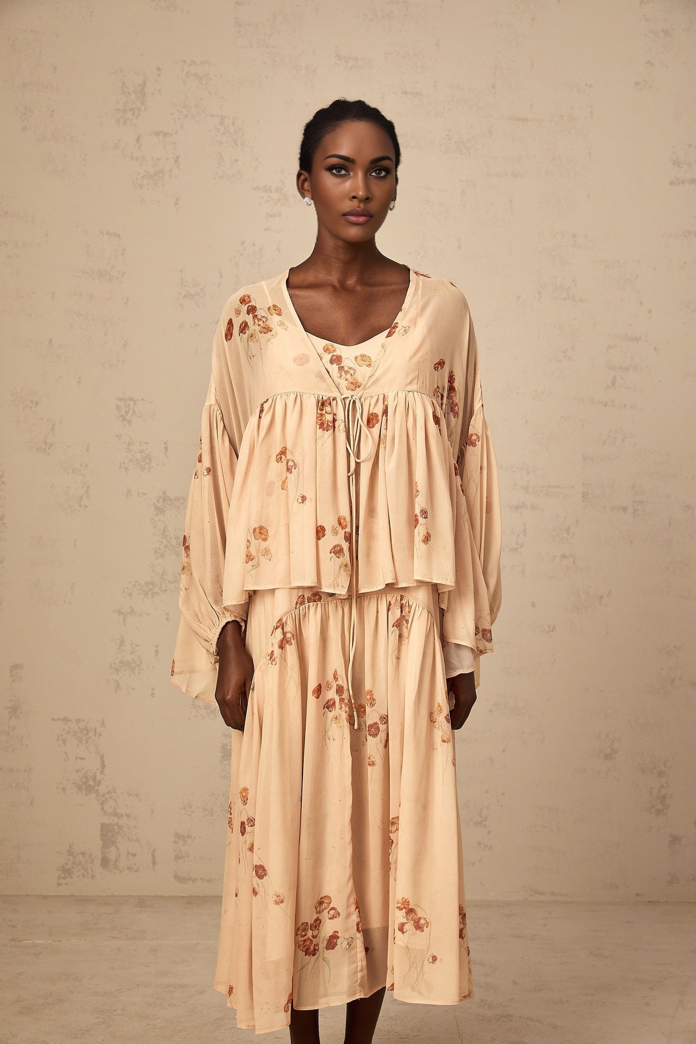 Woman wearing coralpink floral print matching blouse and dress set Blouse has pleated details Dress is sleeveless with a flowy skirt