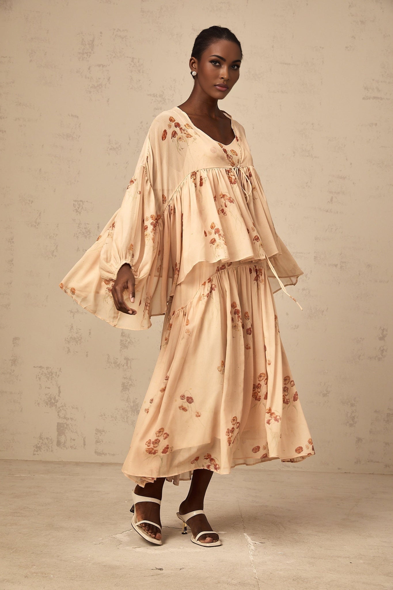 Woman wearing coralpink floral print matching set with pleated blouse and dress Maia collection