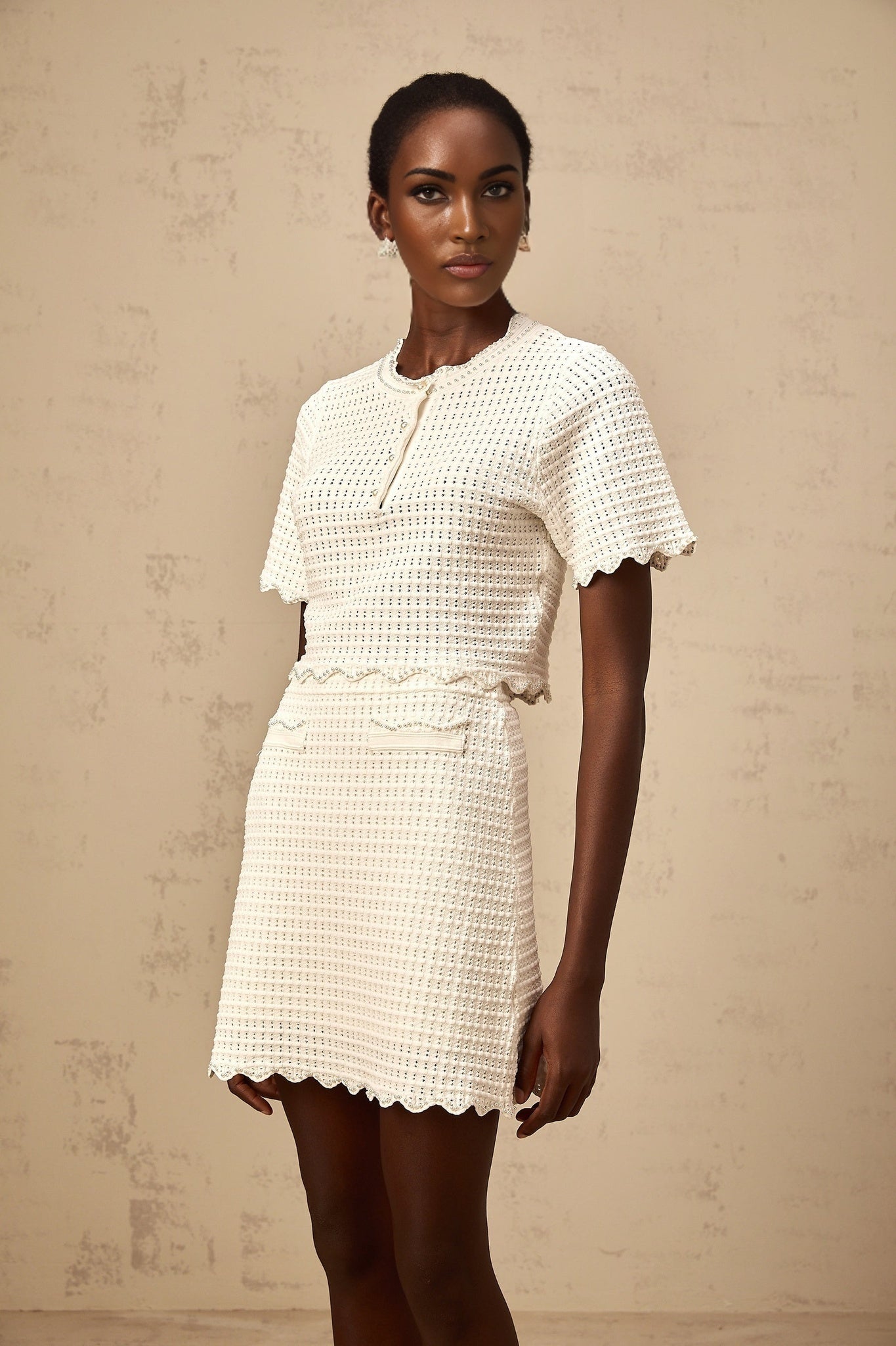 Woman wearing creamwhite knit top and skirt set featuring ruffles and pointelle details Maxanne matching outfit