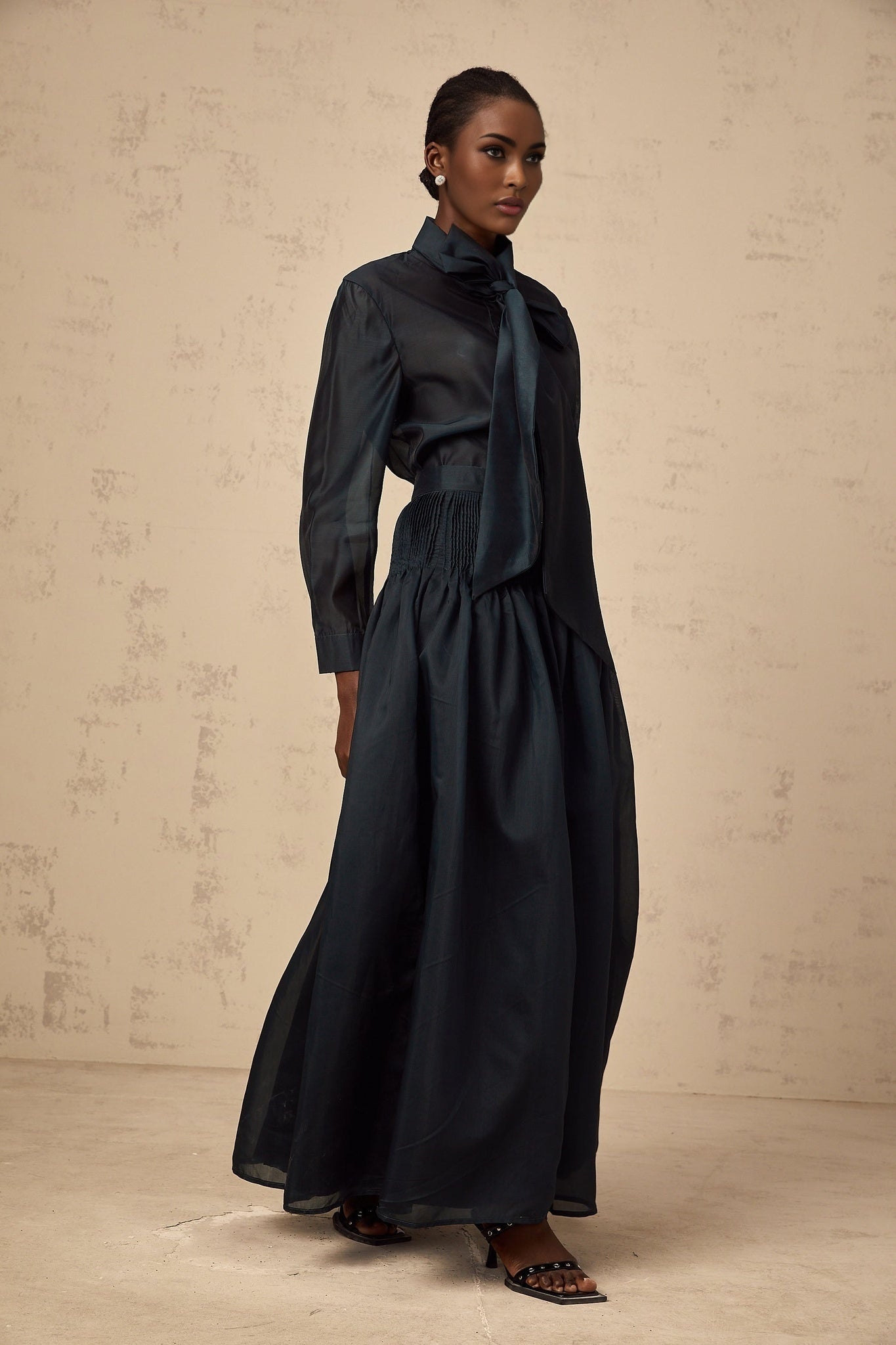 Woman wearing dark green matching shirt and skirt set with ribbon tie neck detail