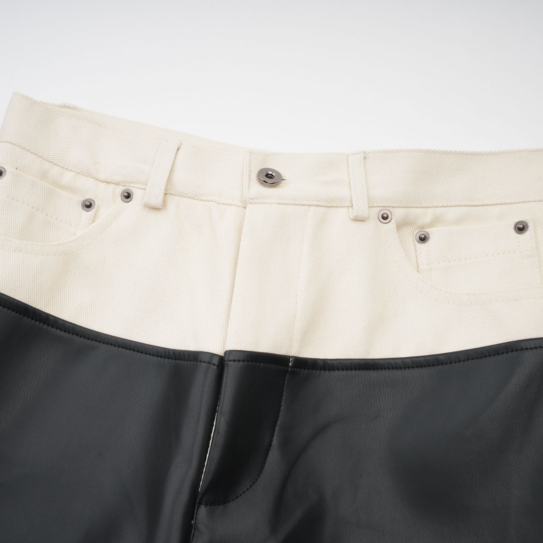 Woman wearing dark leather trousers with contrasting light colored side panels and waistband