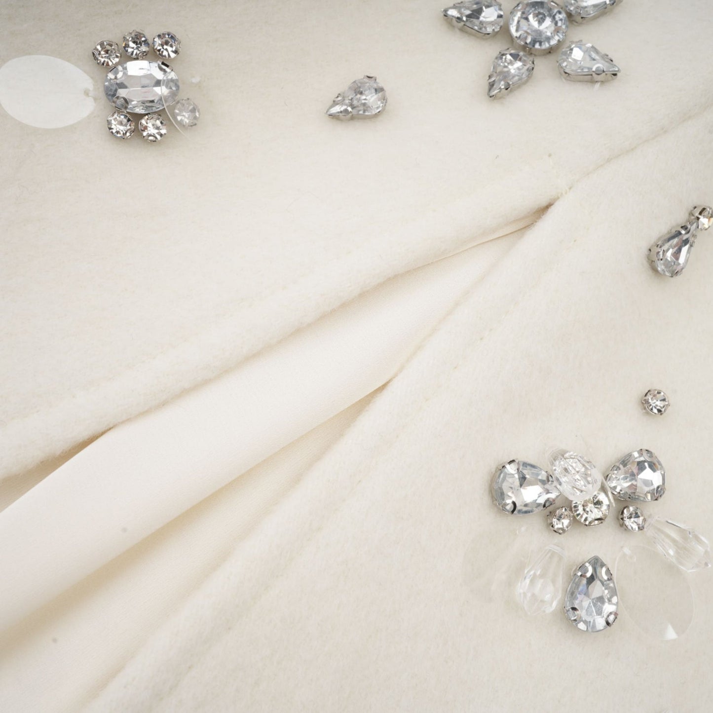 Woman wearing elegant white cape jacket with intricate embellishments and flowing design