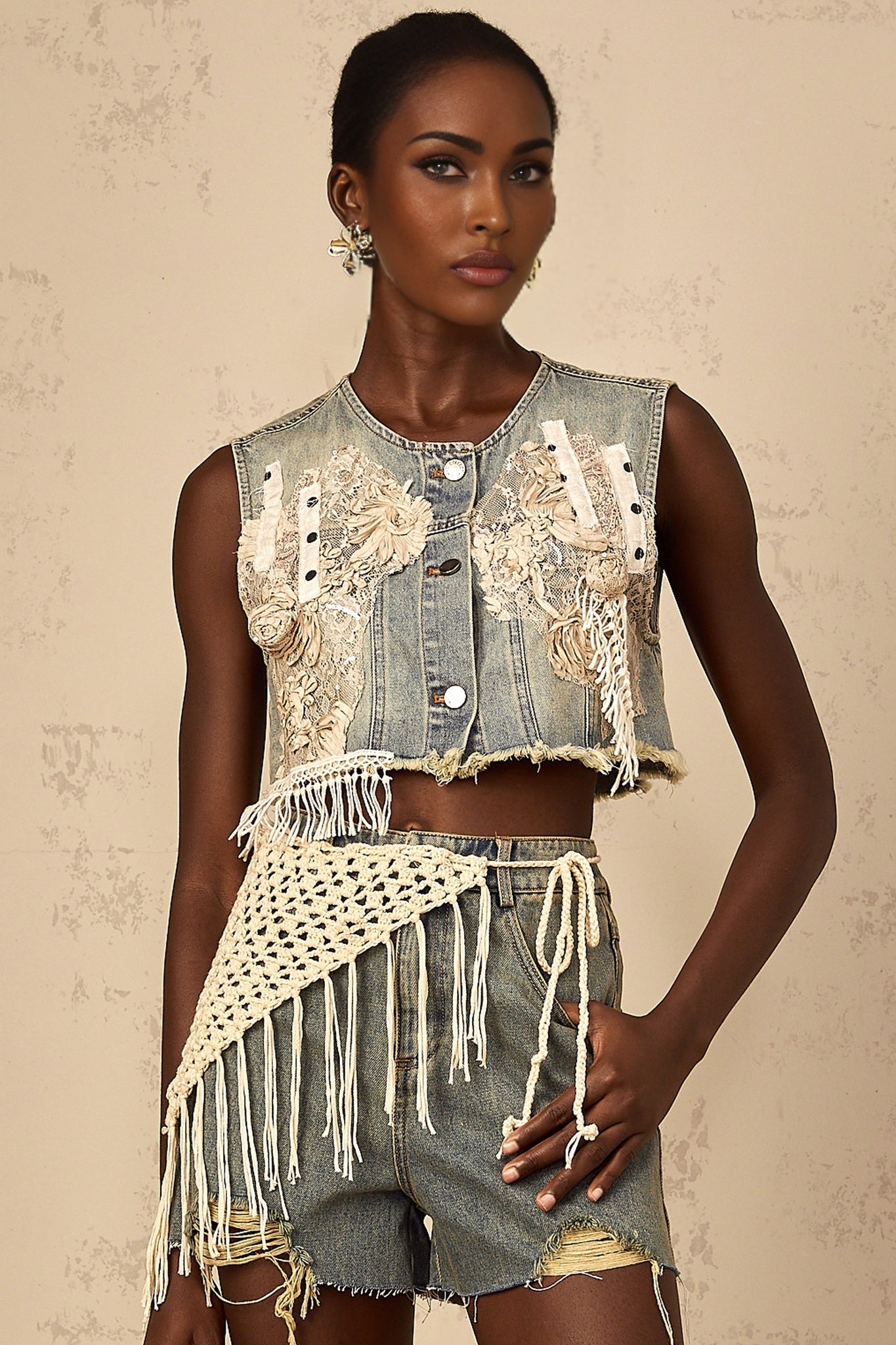 Woman wearing faded blue denim shorts with bohemian style embroidery and distressed details