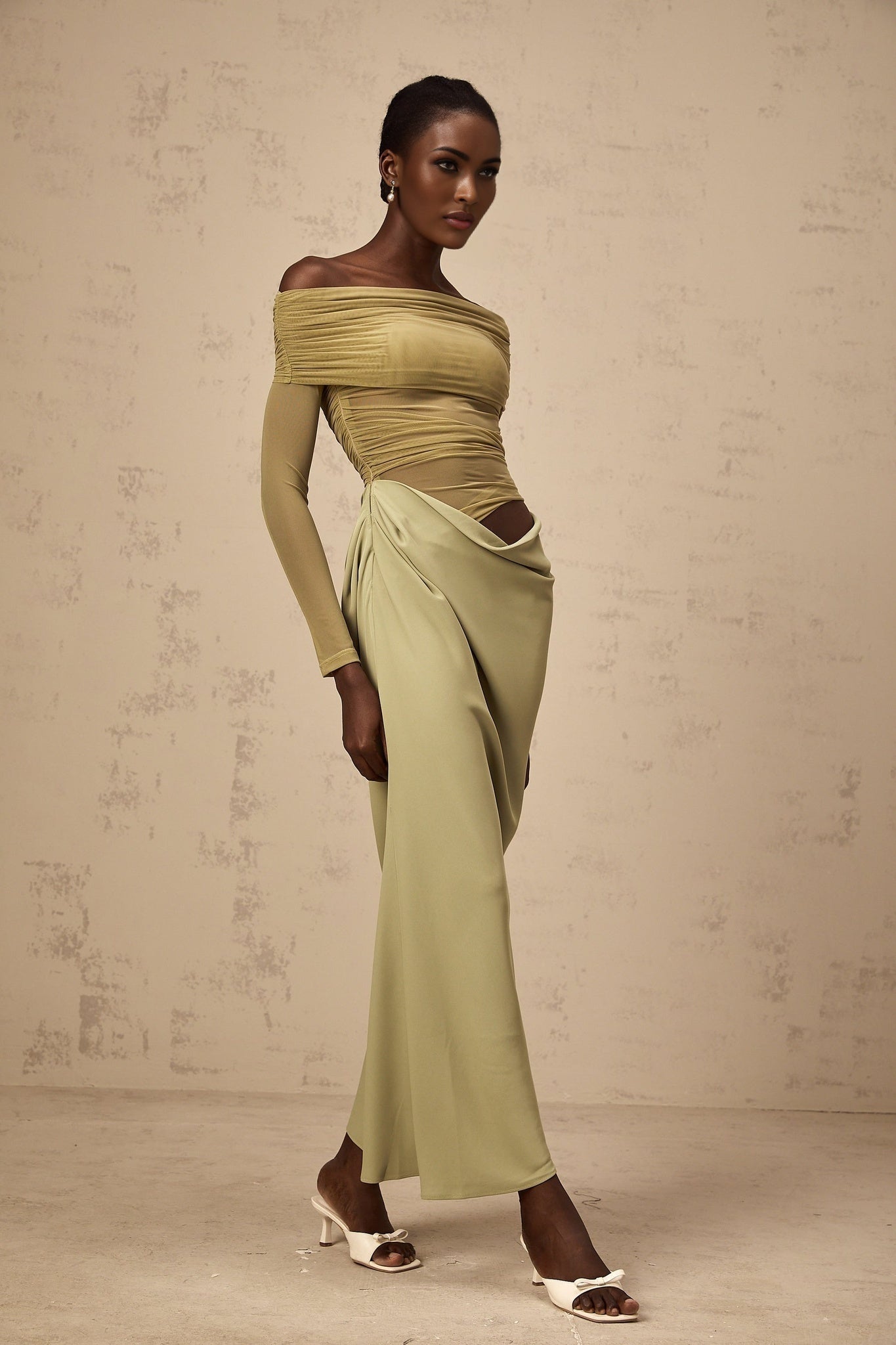 Woman wearing green off shoulder midi dress with sheer elements standing in relaxed pose
