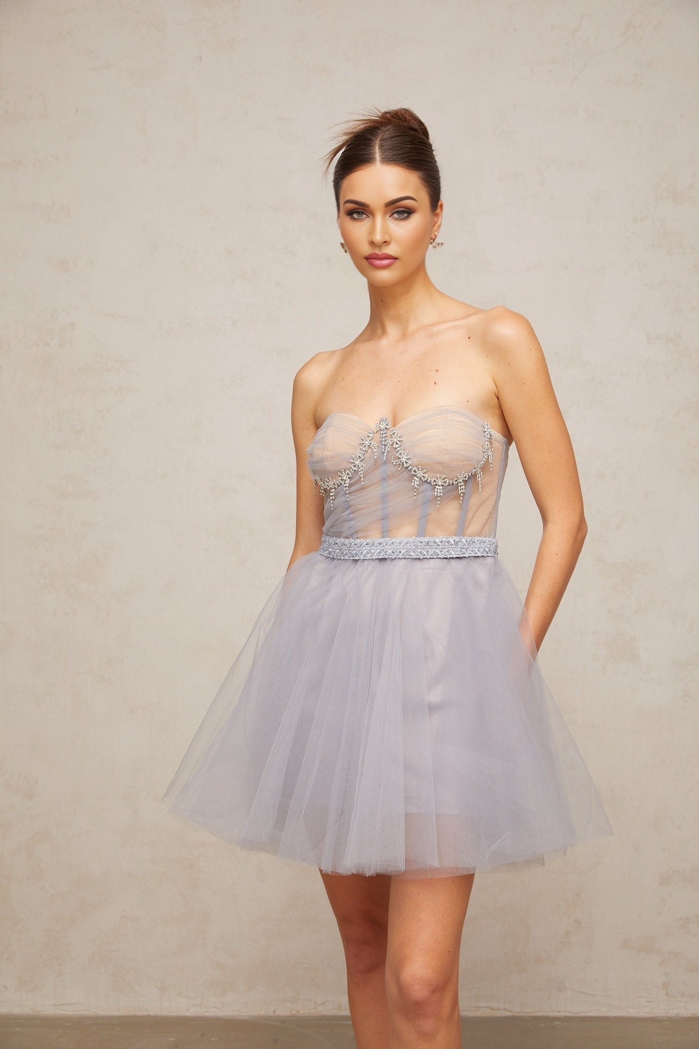 Woman wearing grey mini dress with puffed tulle sleeves and embellished details