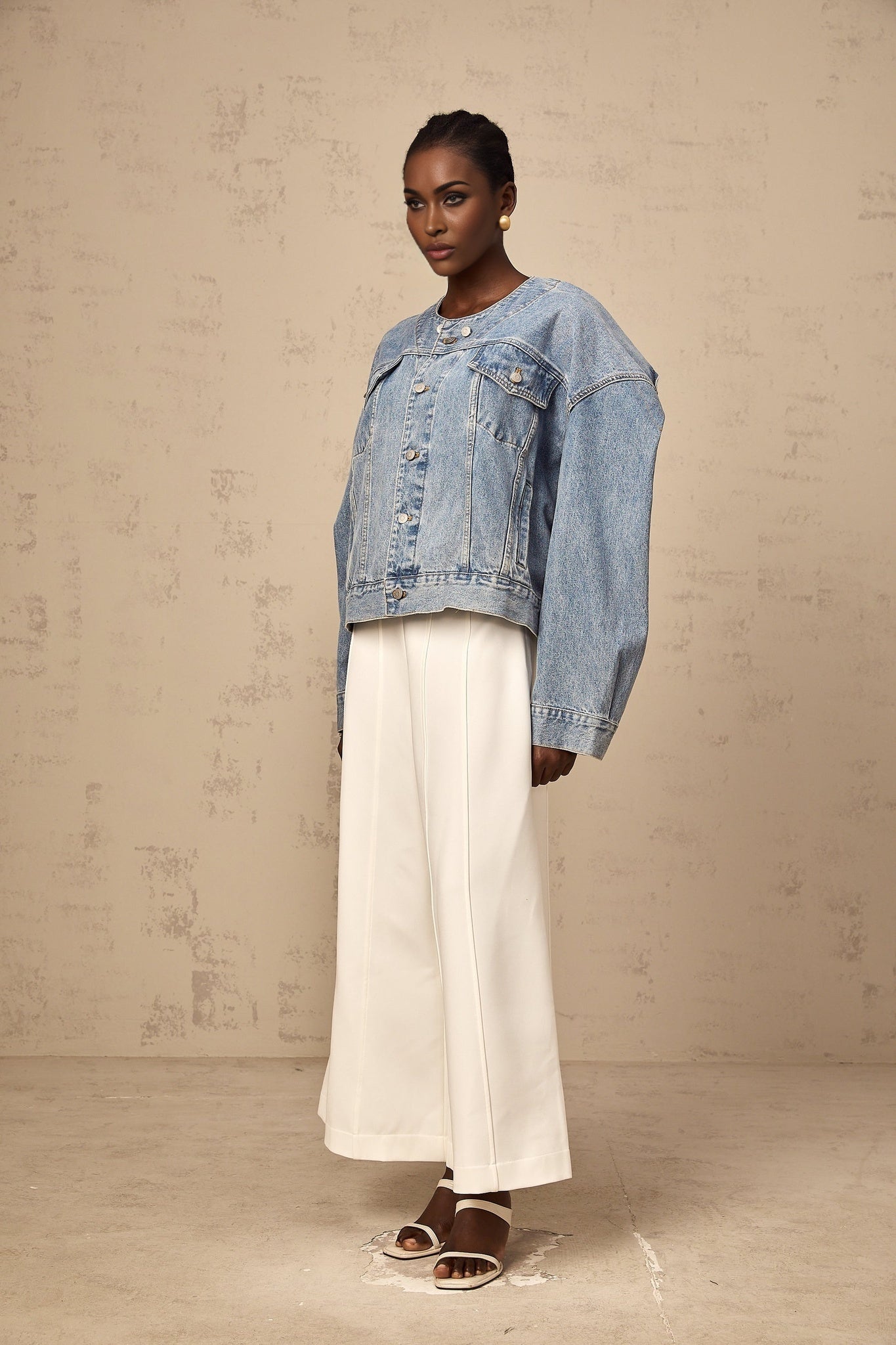 Woman wearing light blue collarless denim jacket with front pockets and button closure