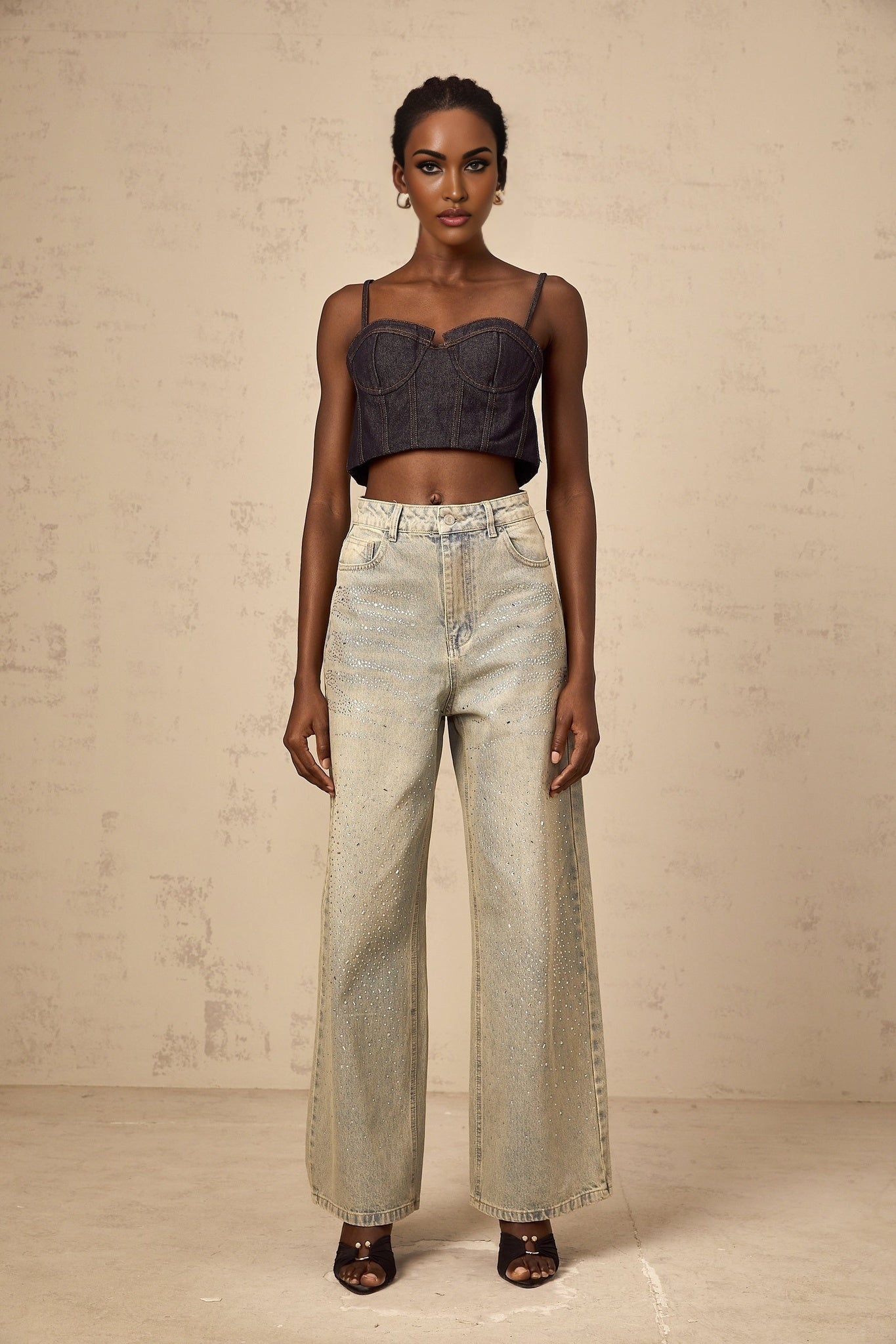 Woman wearing light blue denim jeans with rhinestone embellishments along the pockets and legs