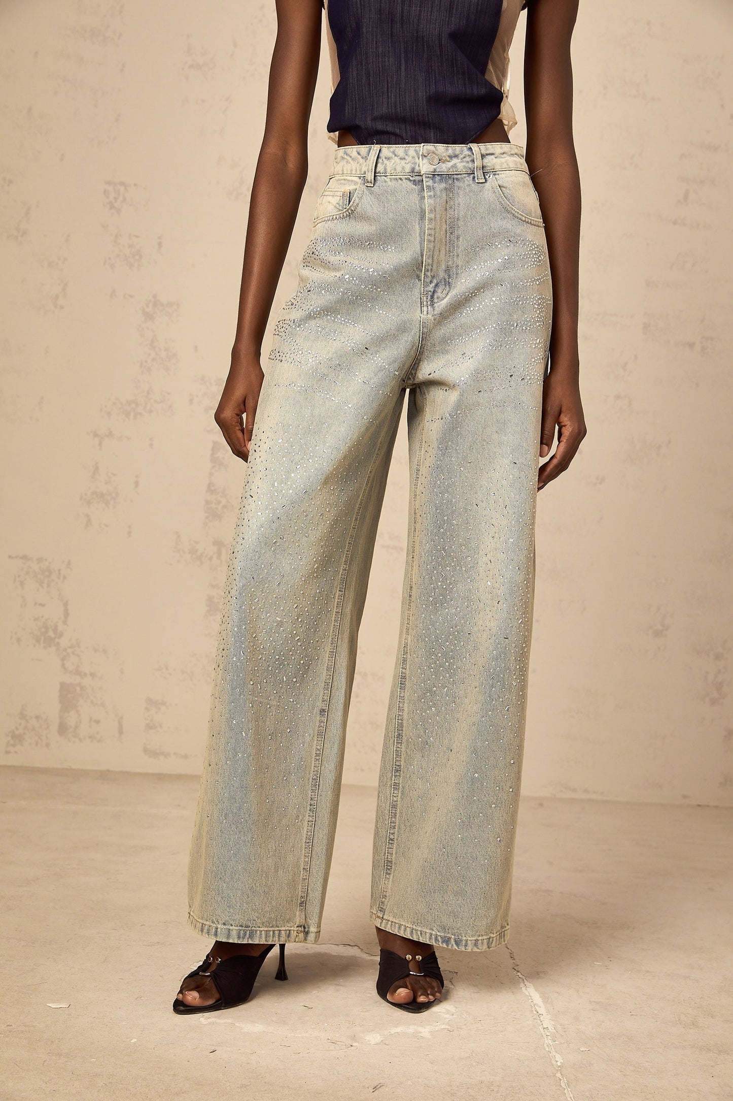 Woman wearing light blue denim jeans with rhinestone embellishments along the sides and pockets