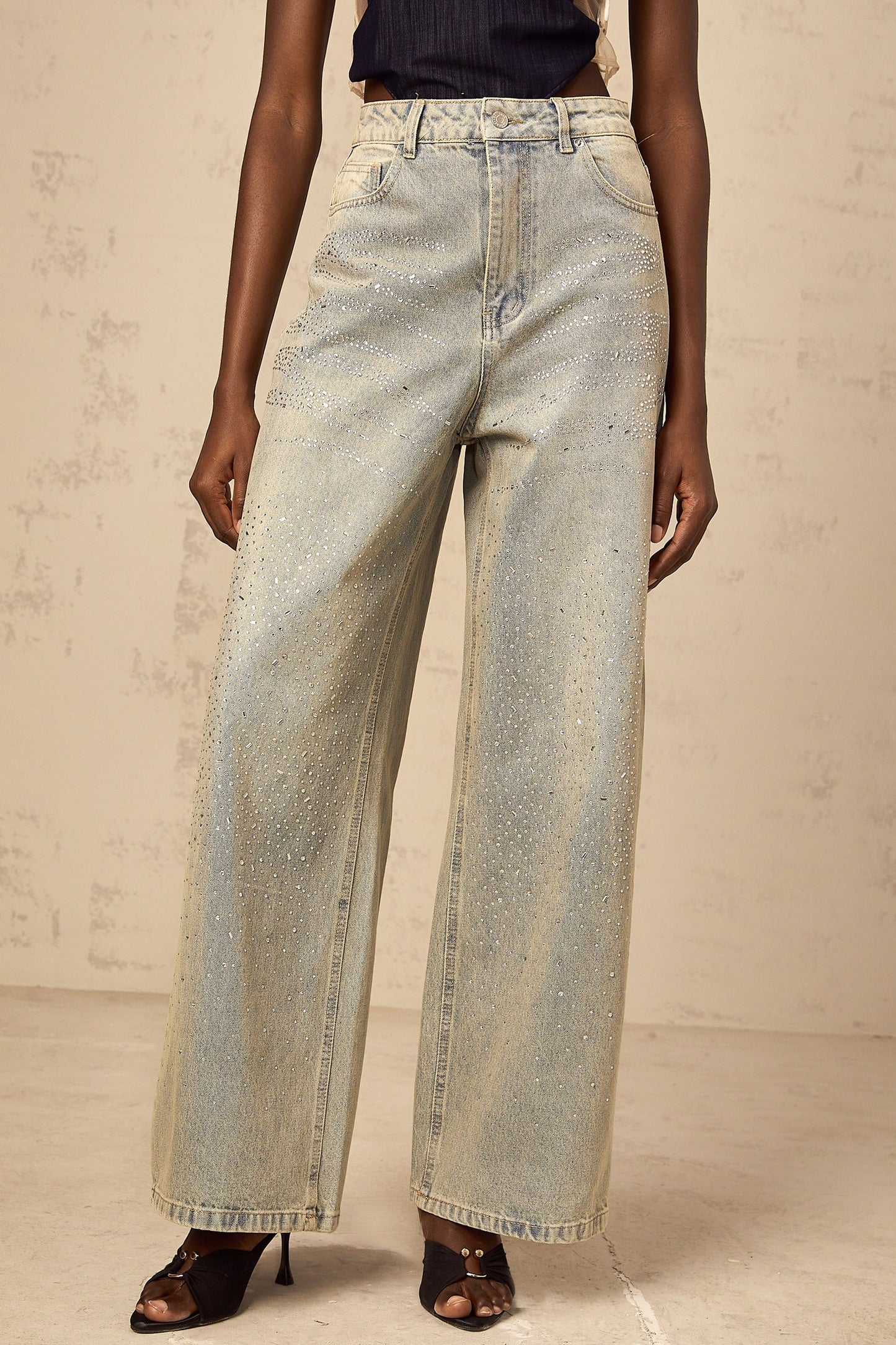 Woman wearing light blue denim jeans with rhinestone embellishments along the sides and pockets
