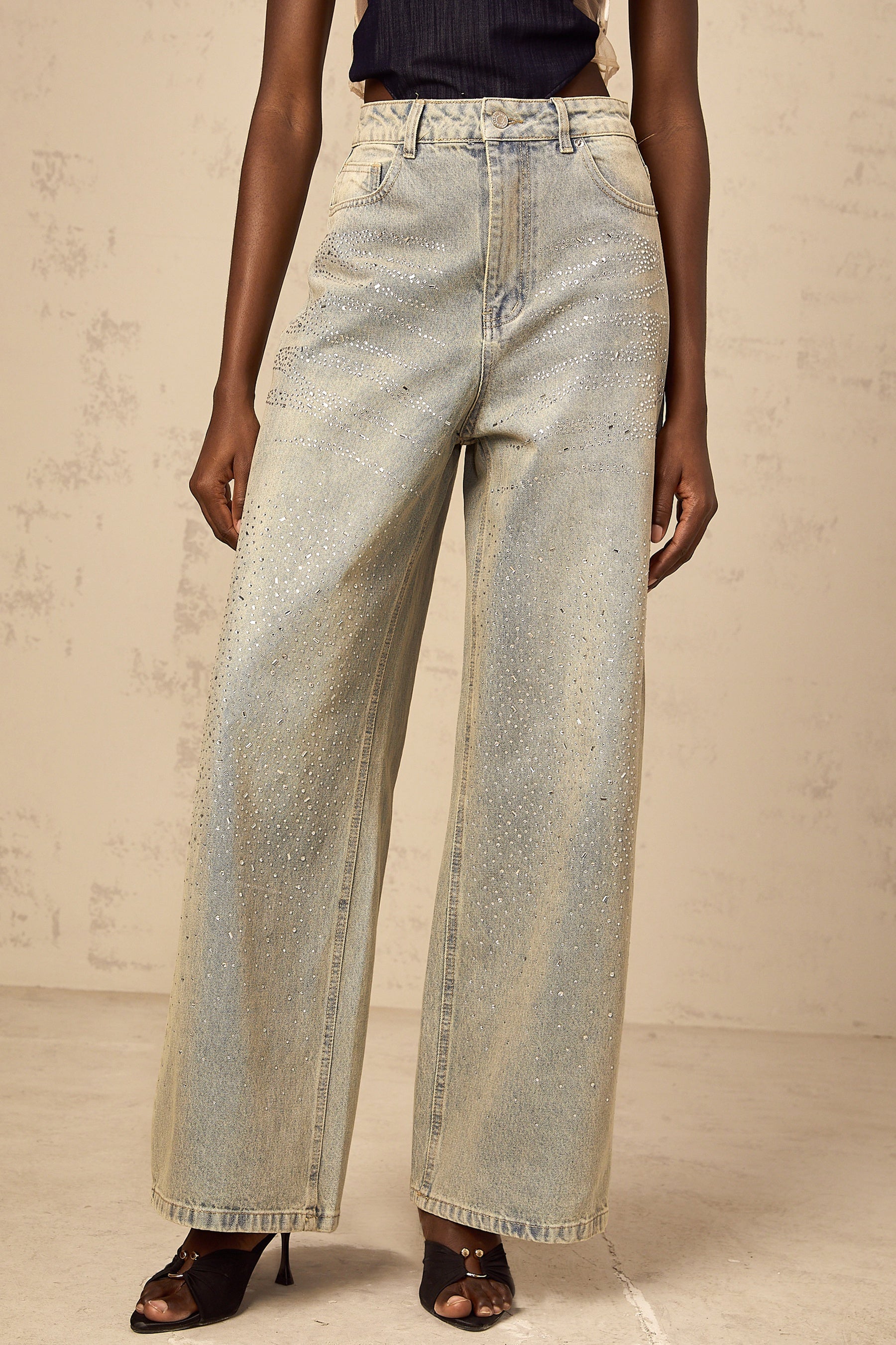 Woman wearing light blue denim jeans with rhinestone embellishments along the sides and pockets