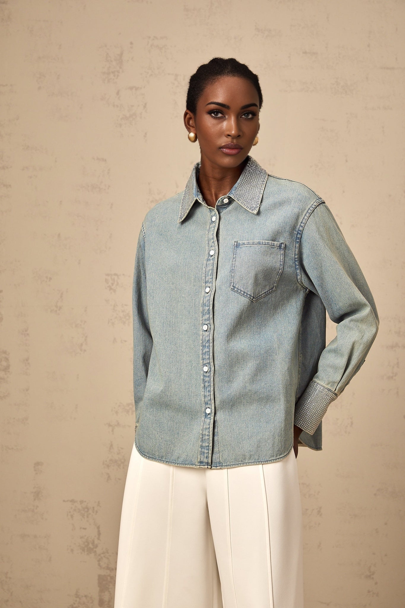Woman wearing light blue denim shirt with rhinestone embellishments on collar and pockets