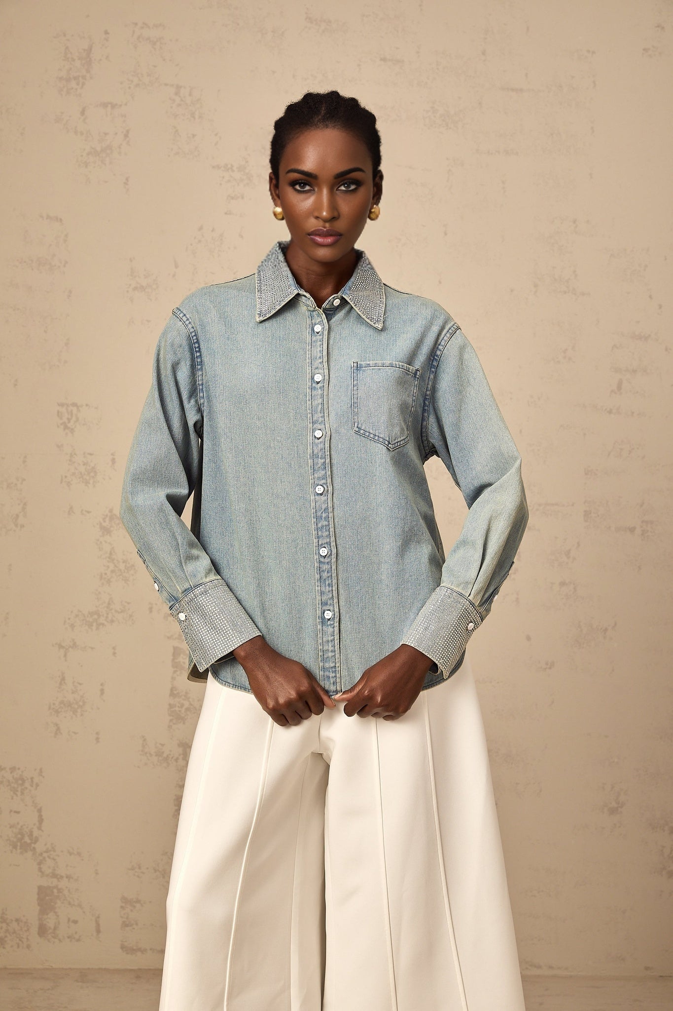 Woman wearing light blue denim shirt with shiny rhinestone embellishments on collar and pockets