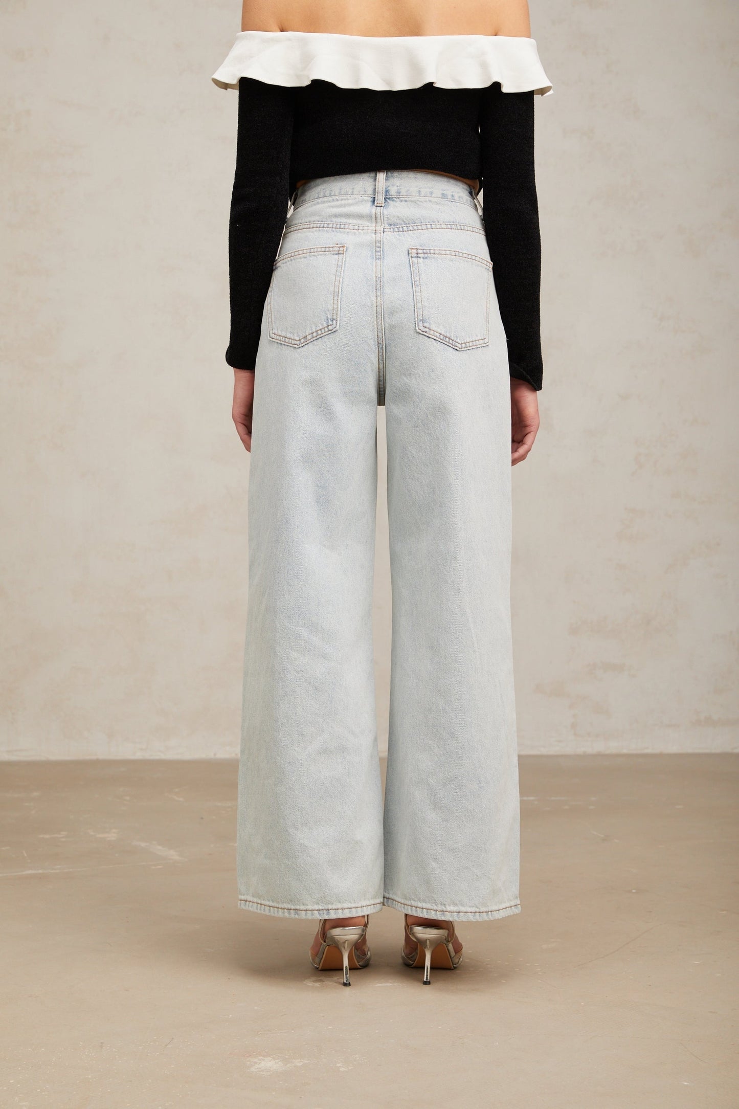 Woman wearing light blue jeans with decorative embellishments standing in a casual pose