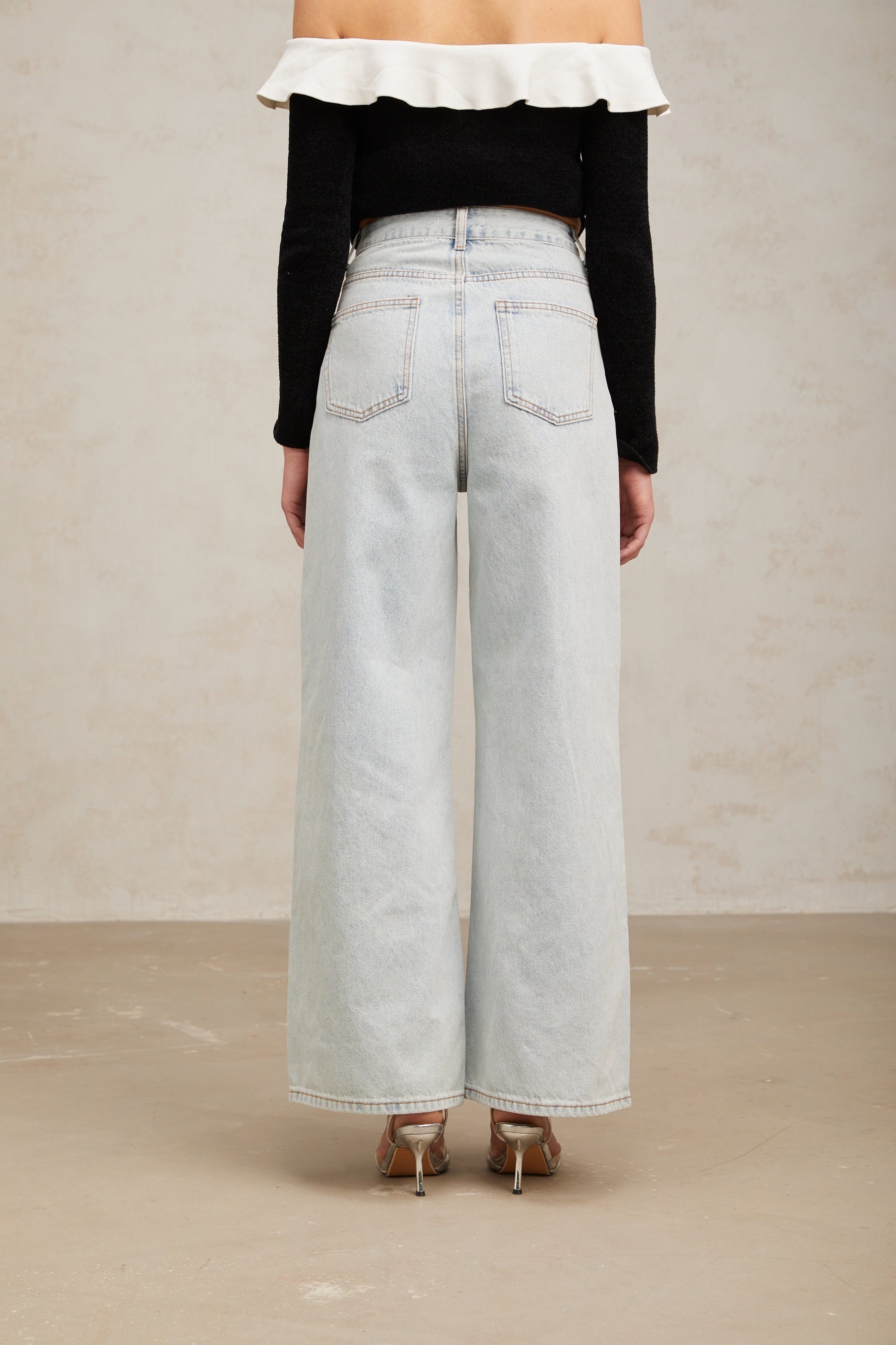 Woman wearing light blue jeans with decorative embellishments standing in a casual pose