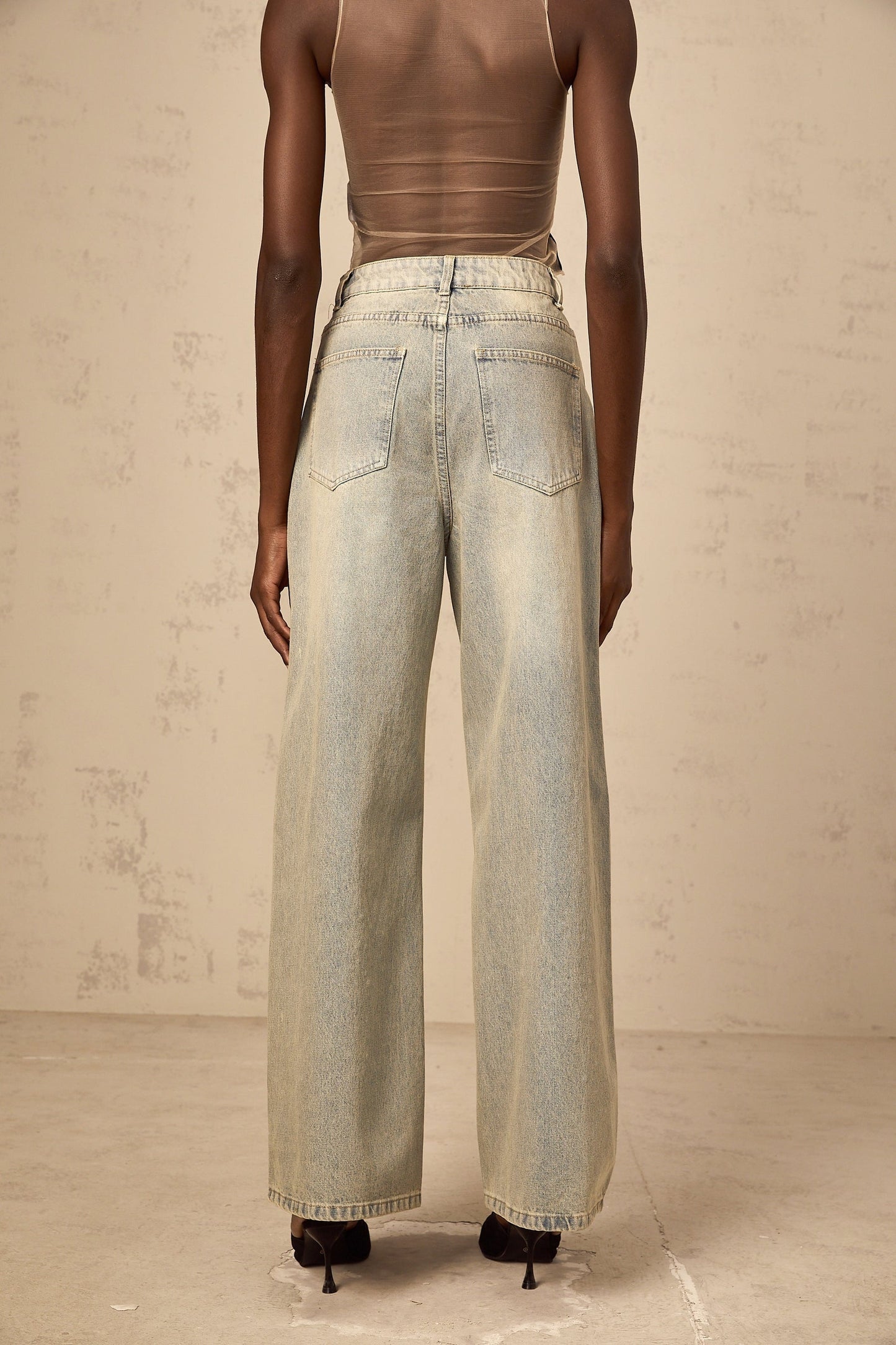 Woman wearing light blue jeans with rhinestone embellishments on the pockets and legs