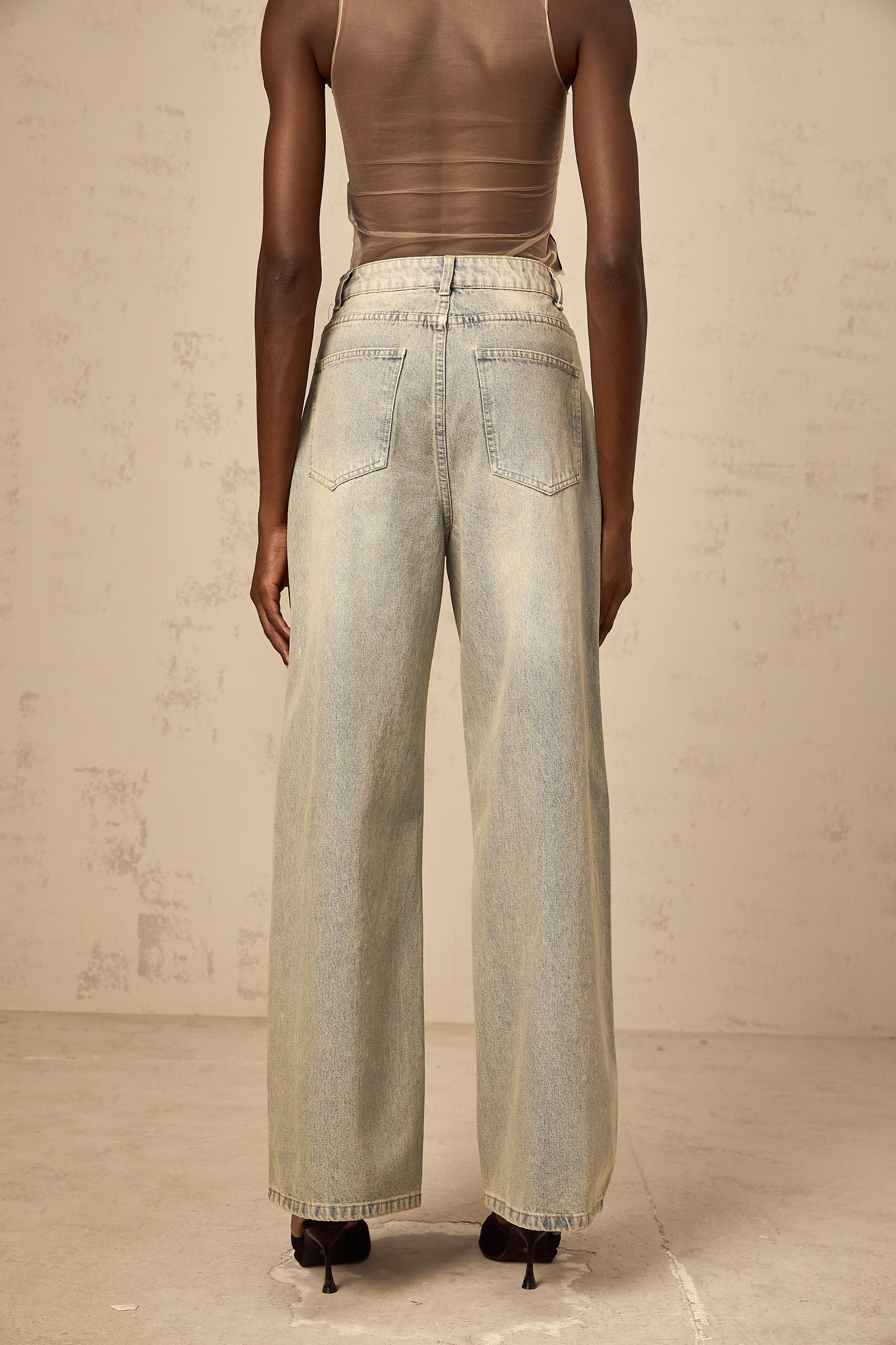 Woman wearing light blue jeans with rhinestone embellishments on the pockets and legs