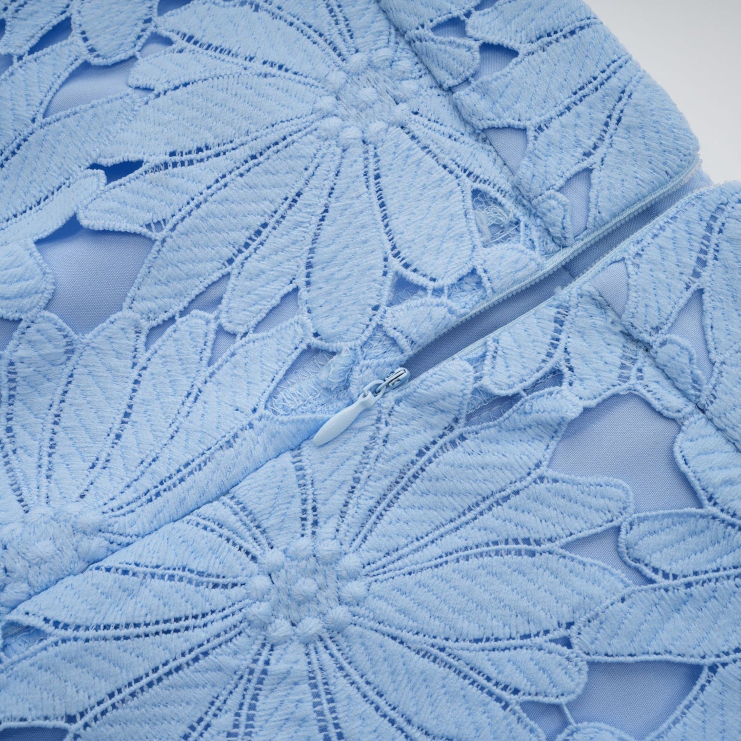 Woman wearing light blue lace top and matching skirt set named Audrey with intricate guipure lace pattern