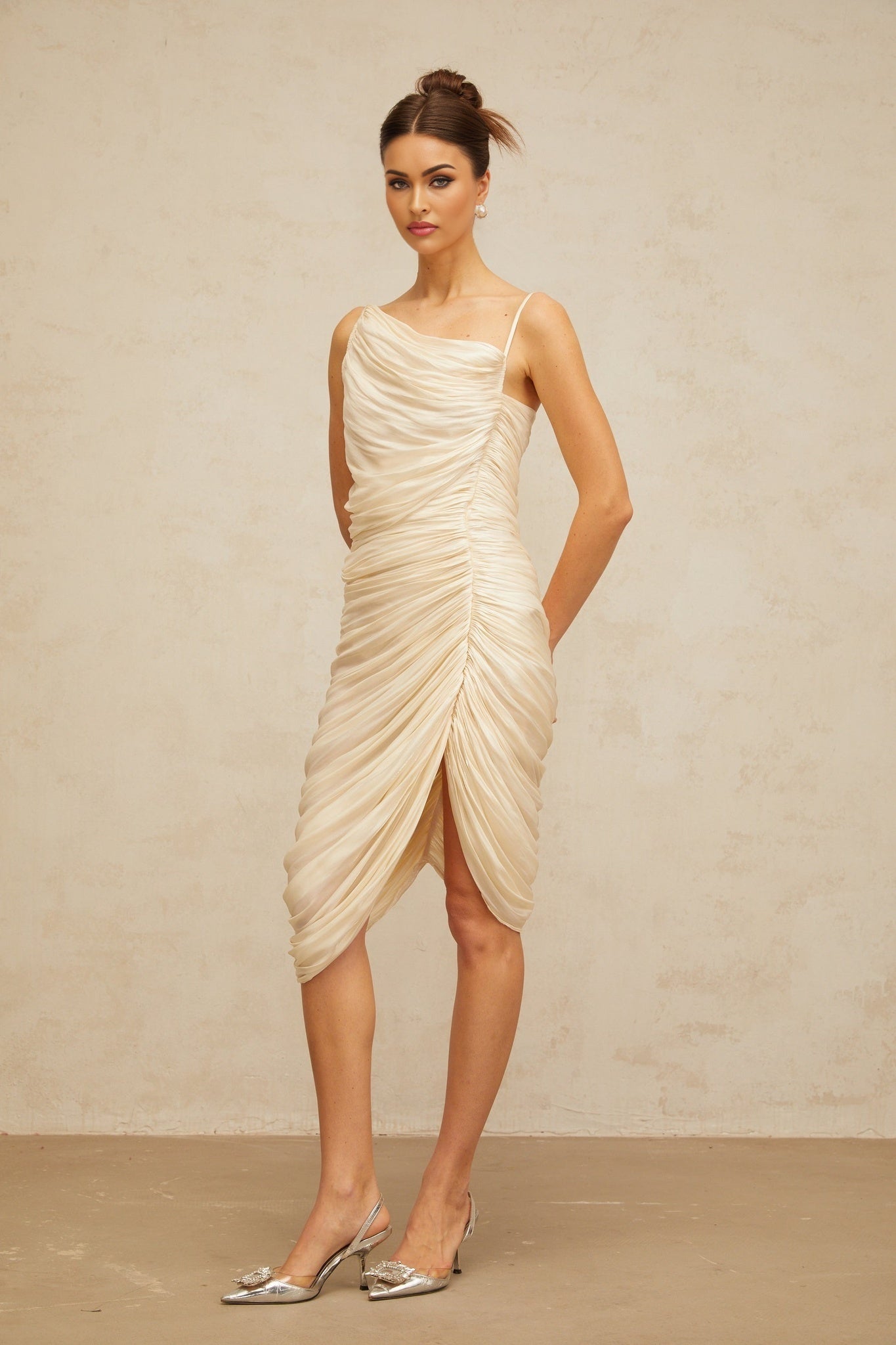 Woman wearing light yellow glossy midi dress with ruched detailing and fitted silhouette
