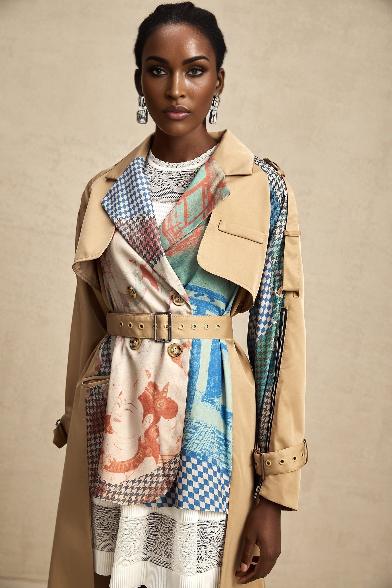 Woman wearing long beige trench coat with contrasting black details and belt tied at waist