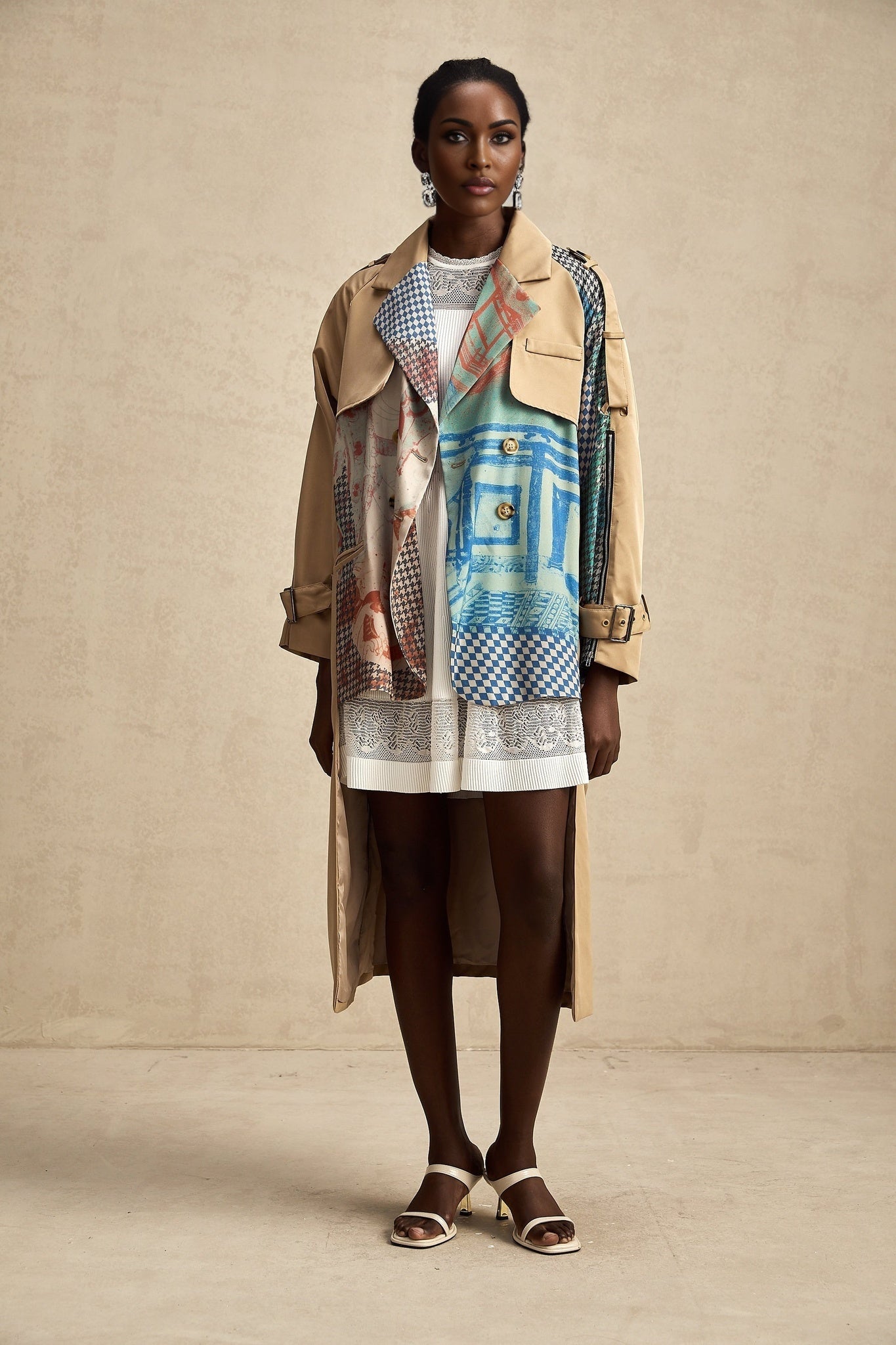 Woman wearing long beige trench coat with contrasting dark trim belt and printed pattern