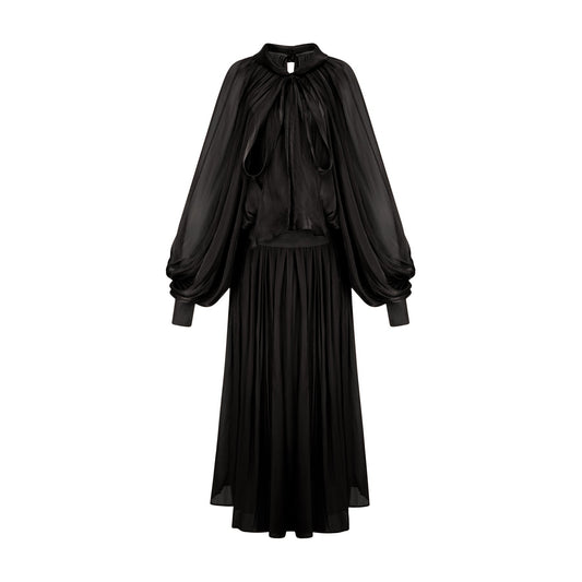Woman wearing long black pleated satin maxi dress with flowing skirt and fitted bodice