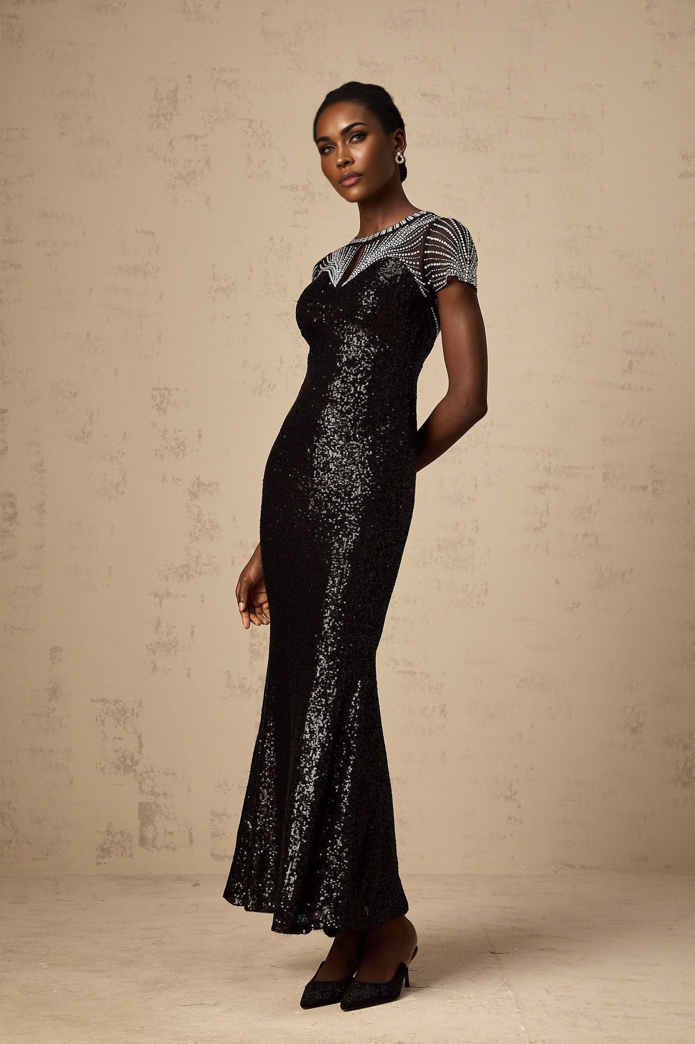 Woman wearing long black sequined maxi dress with cut out details