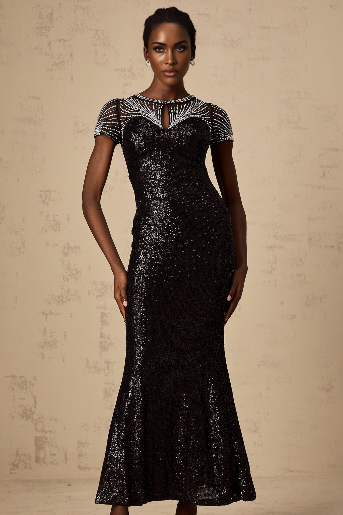 Woman wearing long black sequined maxi dress with cut out details