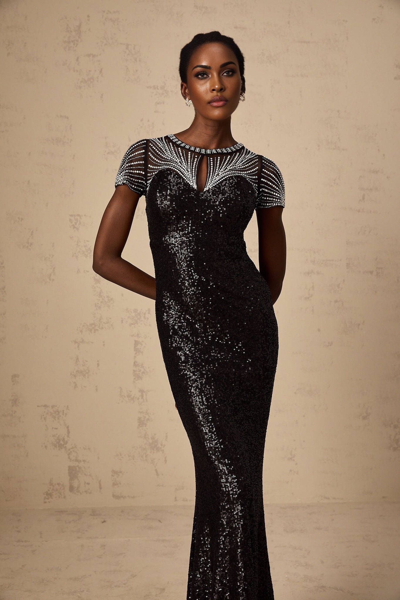 Woman wearing long black sequined maxi dress with cutout detail