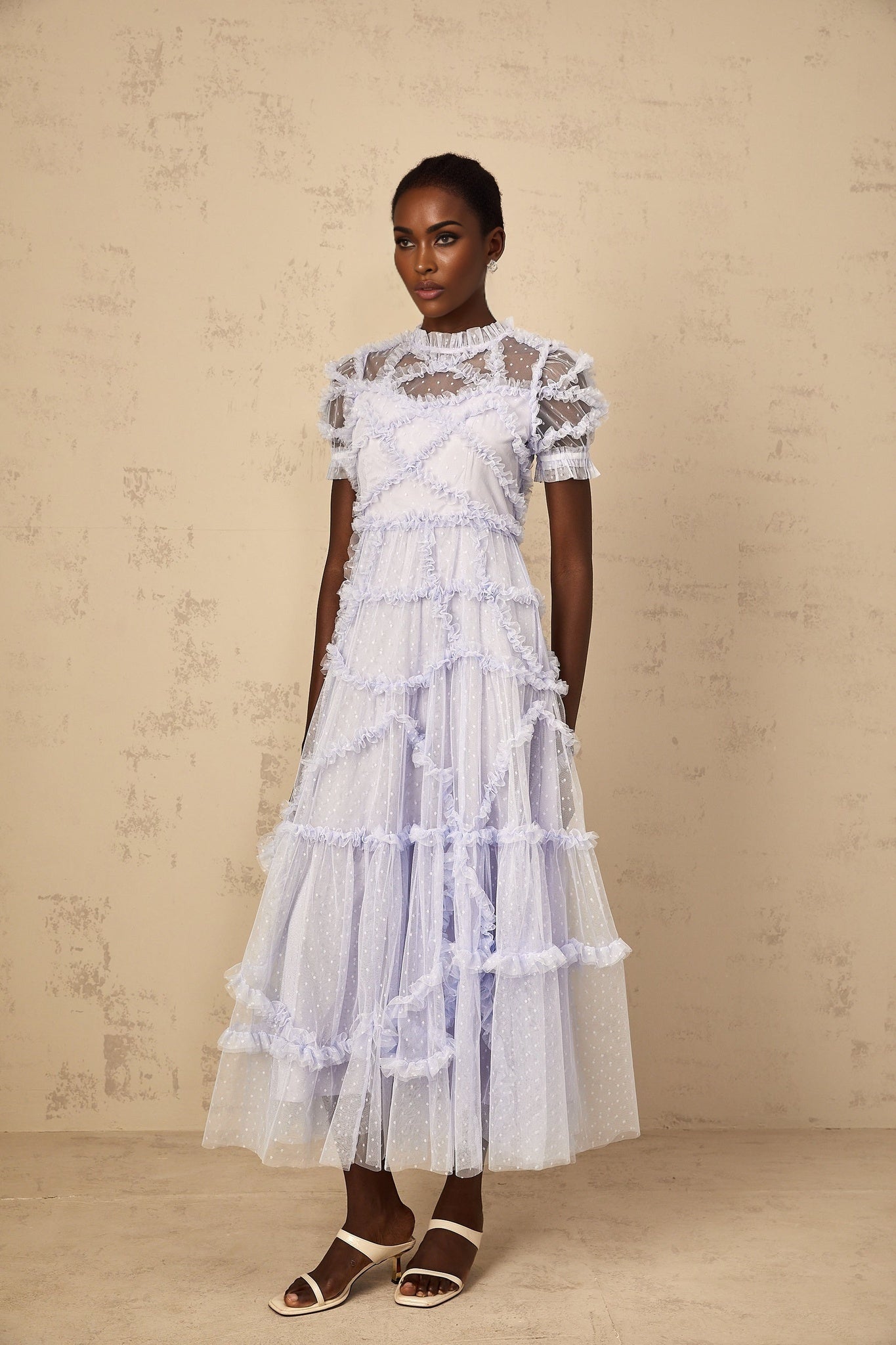 Woman wearing long blue maxi dress with white polka dots and ruffled tulle details