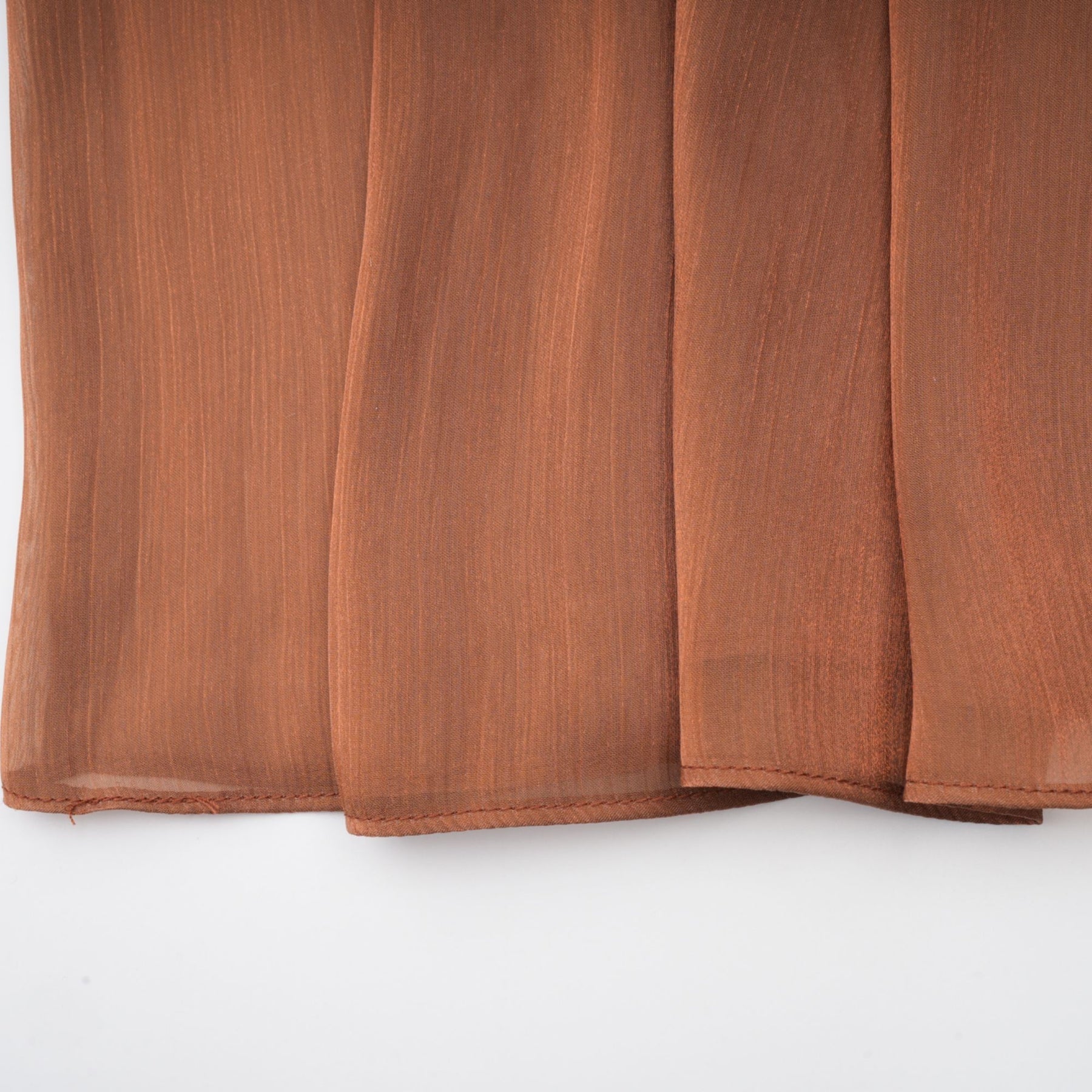 Woman wearing long brown satin maxi dress with pleated details flowing to the floor