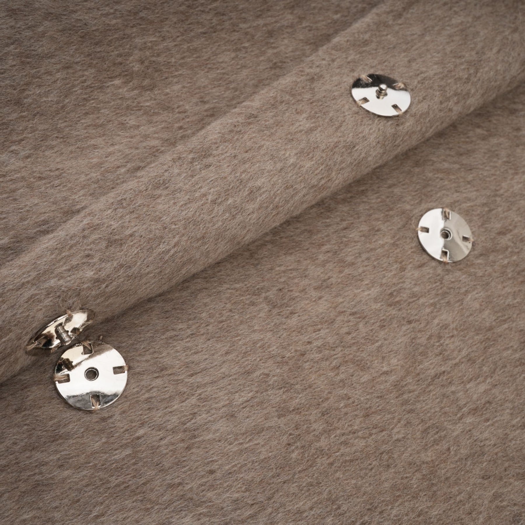 Woman wearing long brown wool cape coat with fur collar and belt cinched at waist