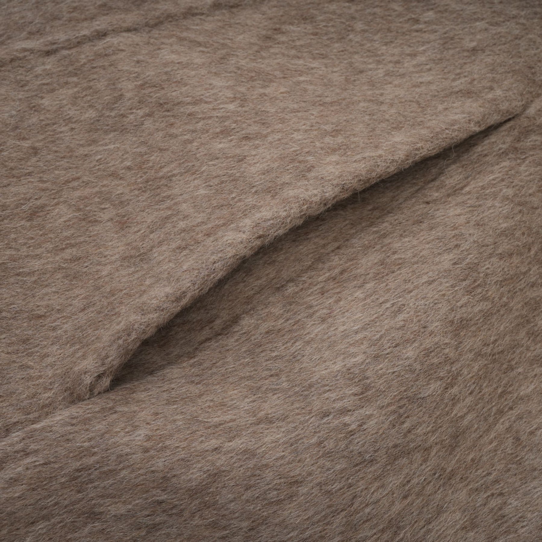 Woman wearing long brown wool coat with fur trim and belt cinched at waist cape style drapes over shoulders