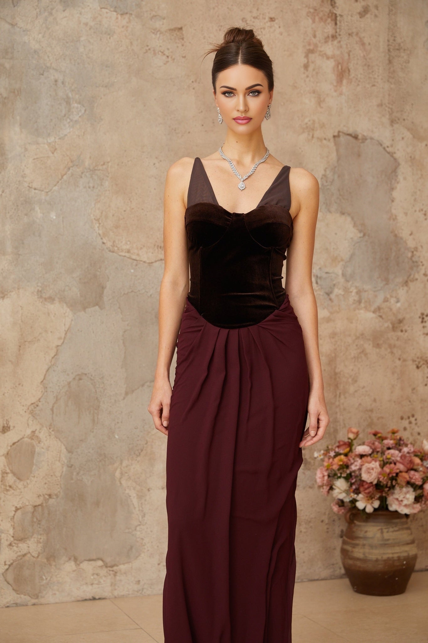 Woman wearing long burgundy maxi dress with velvet panels and shirred detailing