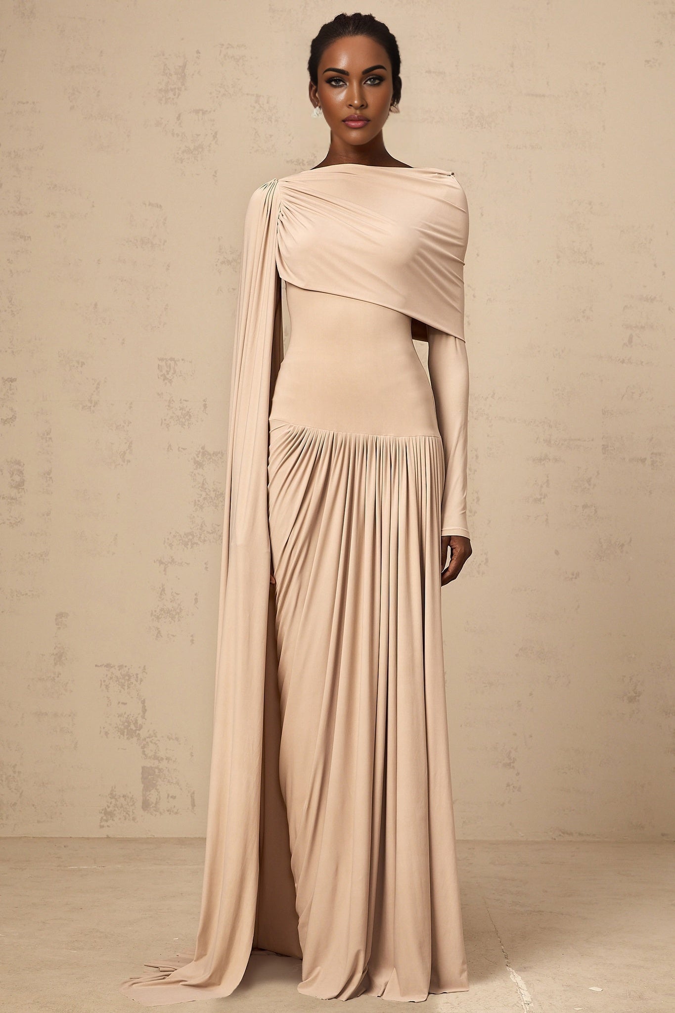 Woman wearing long flowing neutral colored maxi dress with ribbon design details and draped silhouette