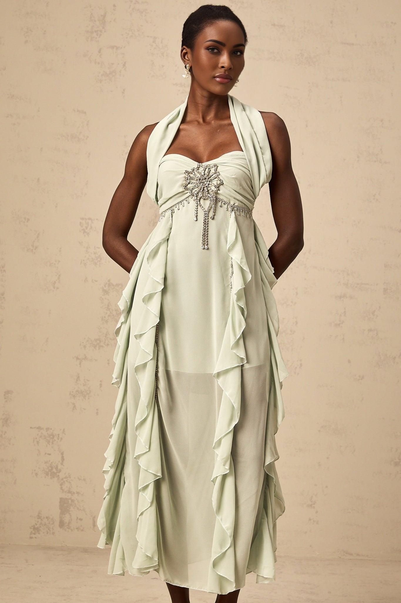 Woman wearing long flowy midi dress with embellished details and ruffled accents