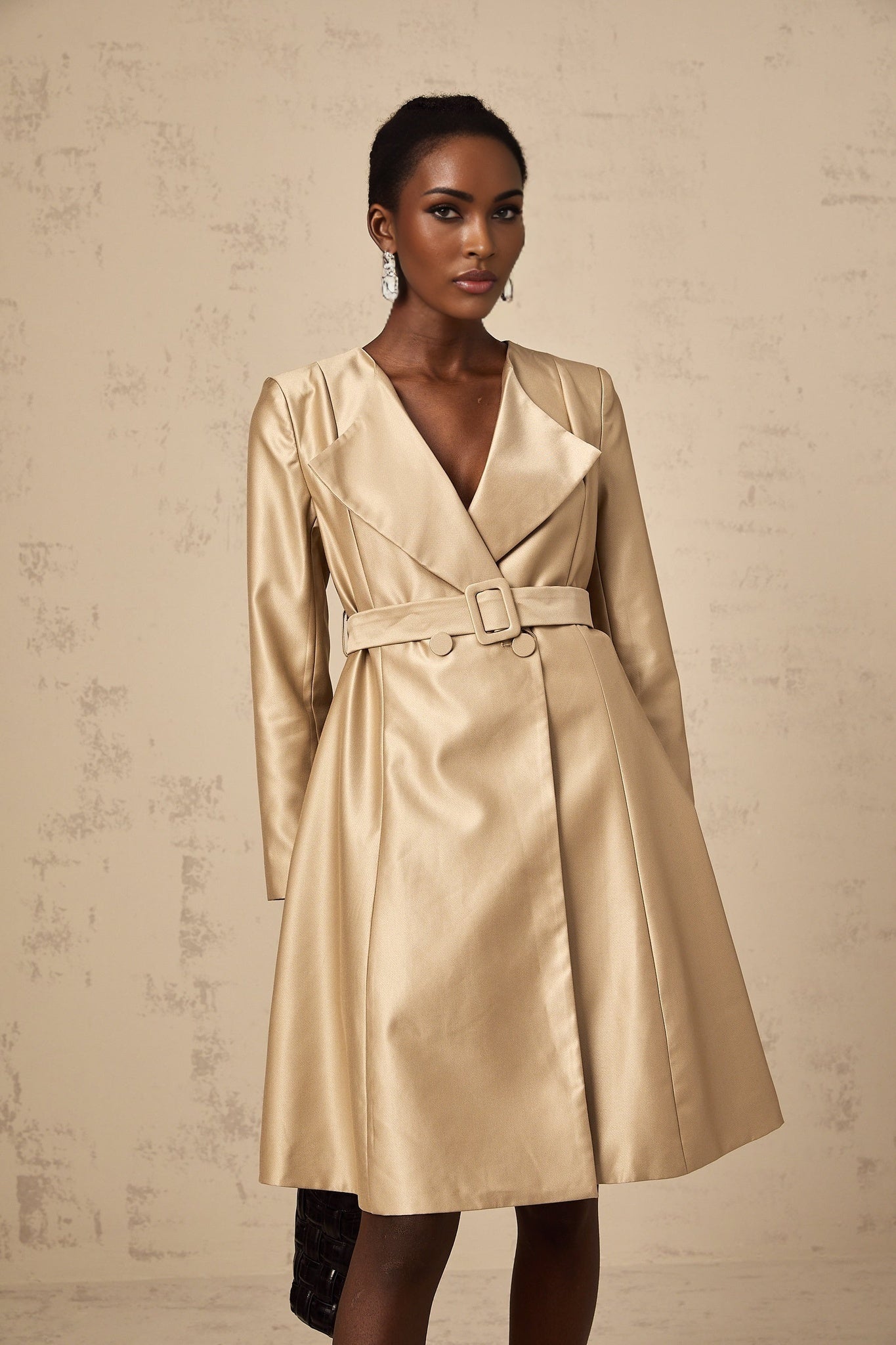 Woman wearing long khaki coat with belted waist and open front