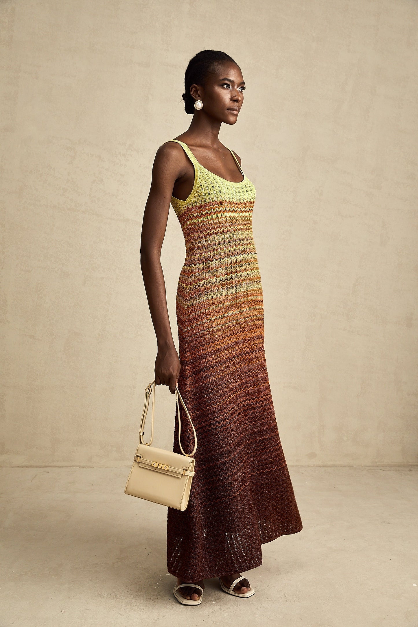 Woman wearing long knitted maxi dress with gradient color pattern from light to dark