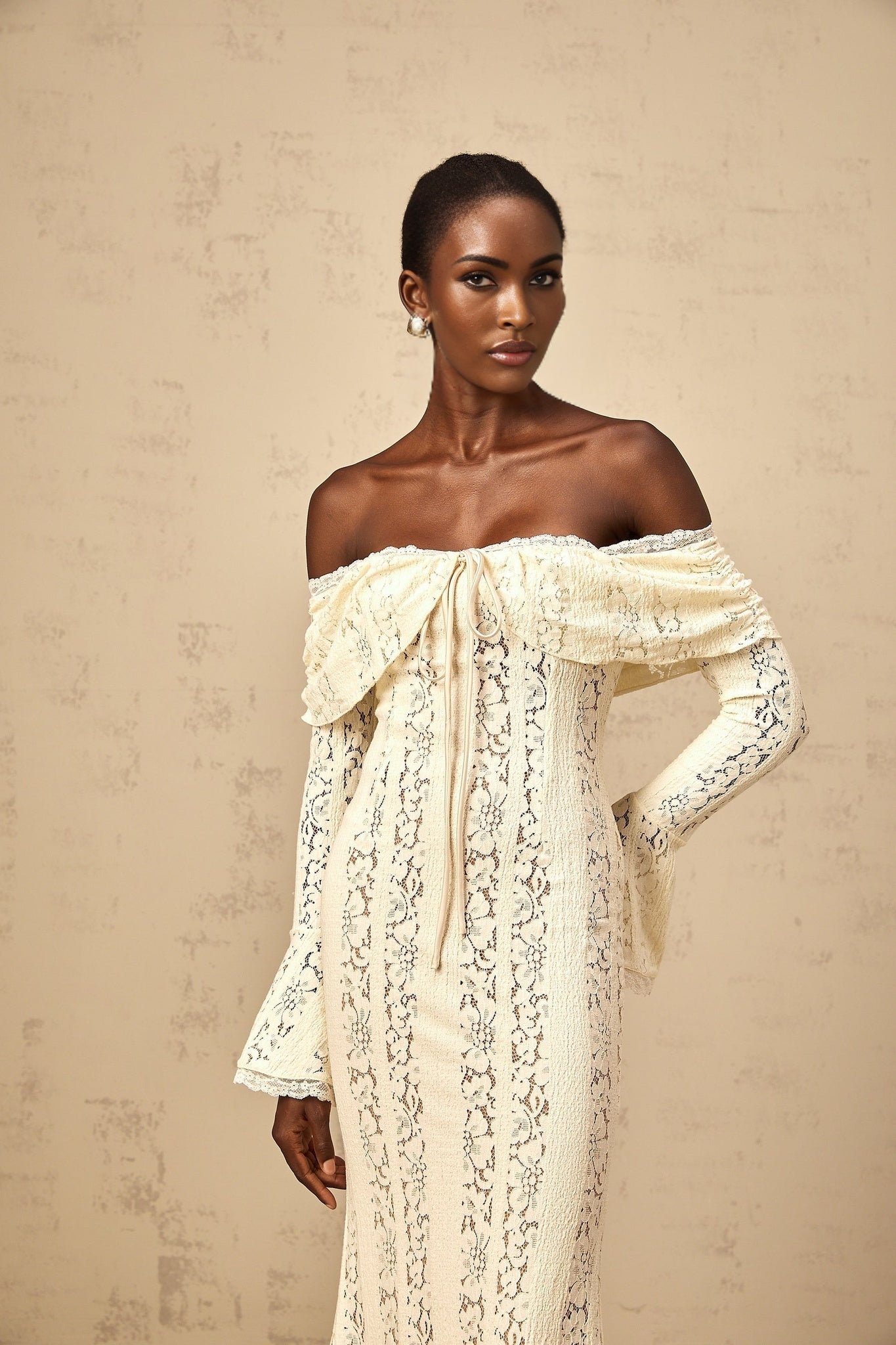 Woman wearing long neutral colored floral lace maxi dress with train design