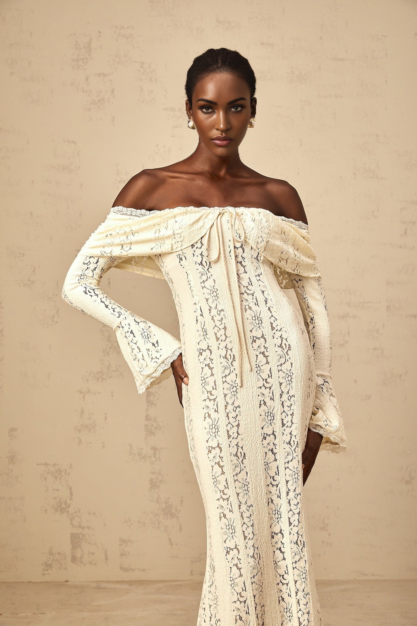Woman wearing long neutral colored floral lace maxi dress with train design