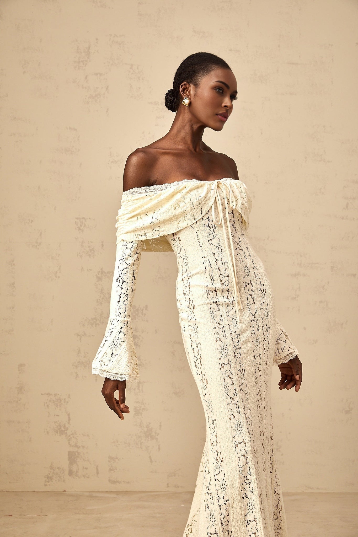Woman wearing long neutral colored floral lace maxi dress with train detail