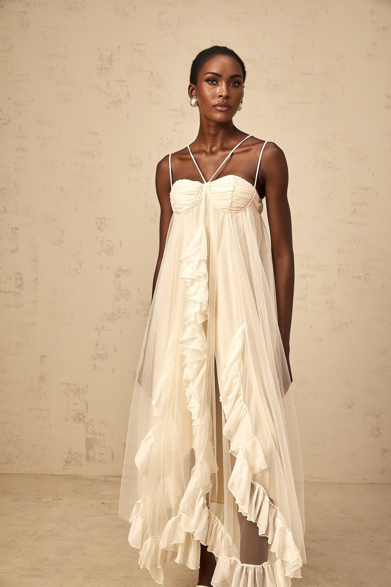 Woman wearing long neutral colored maxi dress with layered ruffled tulle skirt and fitted bodice
