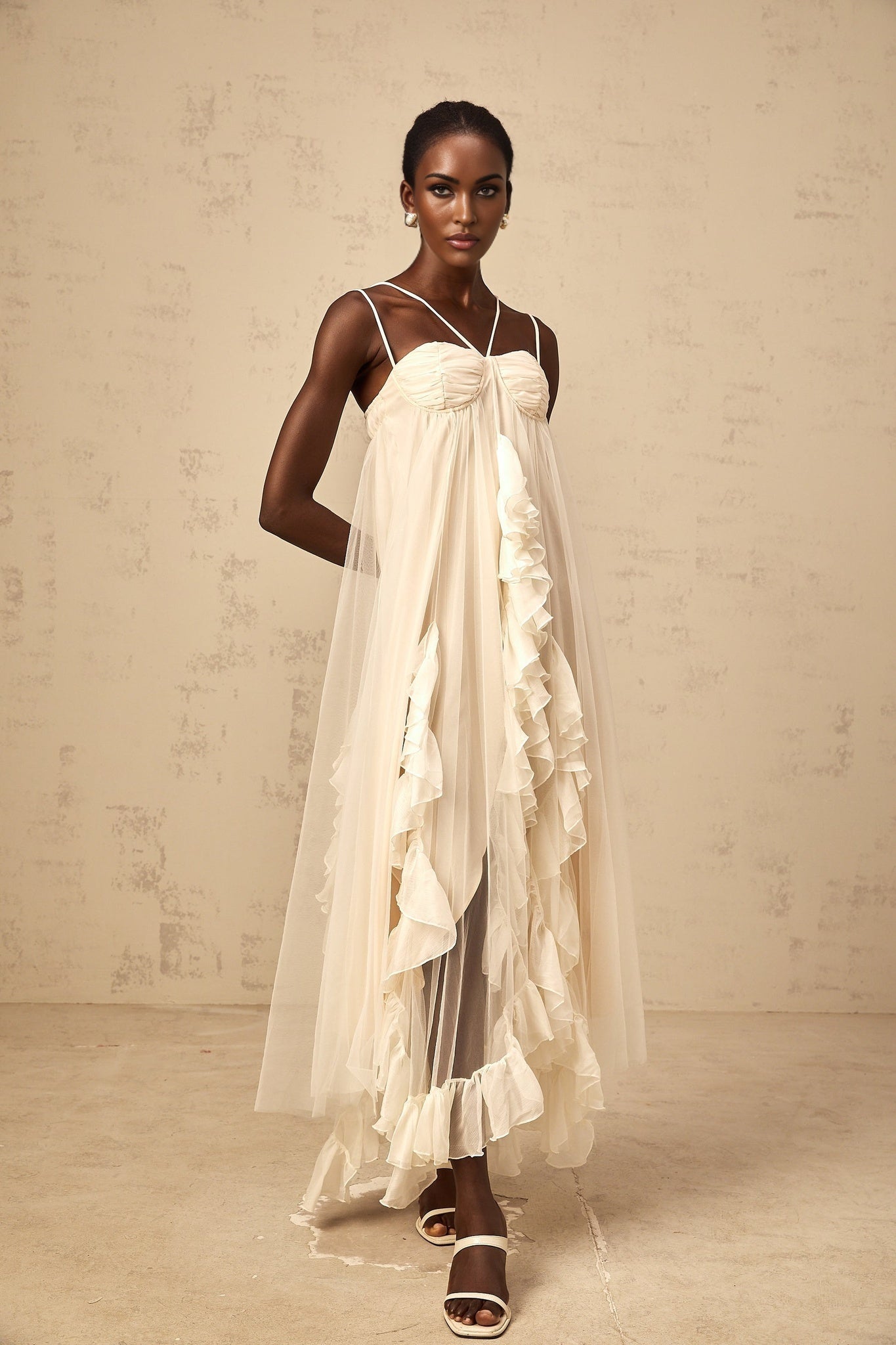Woman wearing long neutral colored maxi dress with layered ruffled tulle skirt and fitted bodice