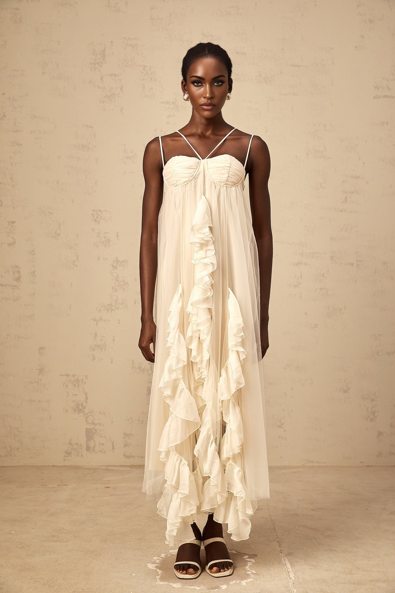 Woman wearing long neutral colored maxi dress with layered ruffled tulle skirt and sleeveless bodice