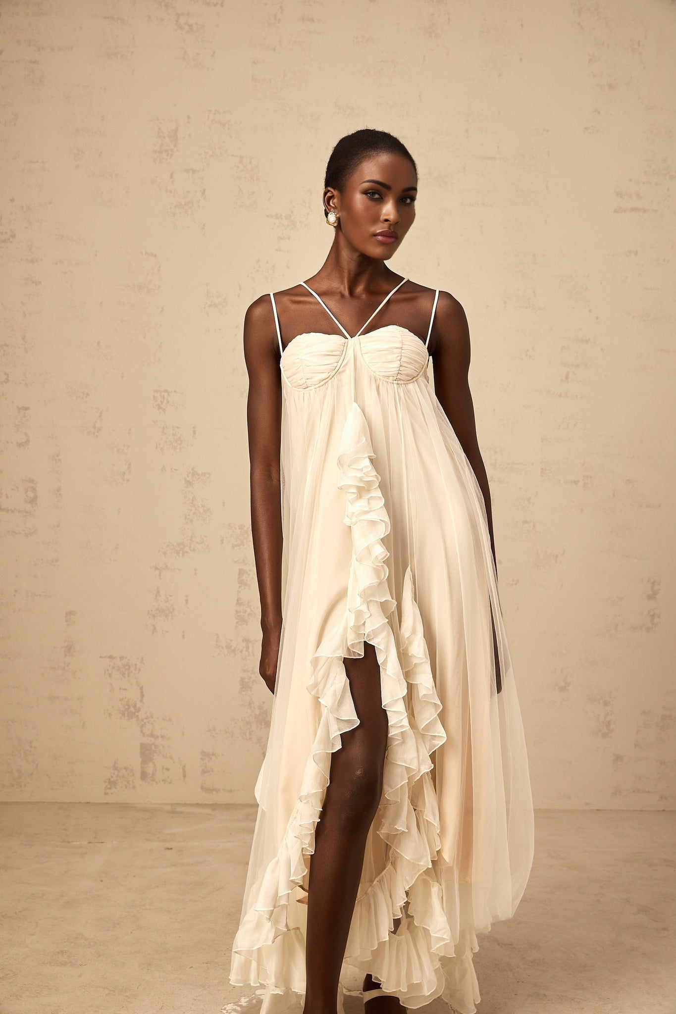 Woman wearing long neutral colored tulle maxi dress with layered ruffles and tiered skirt