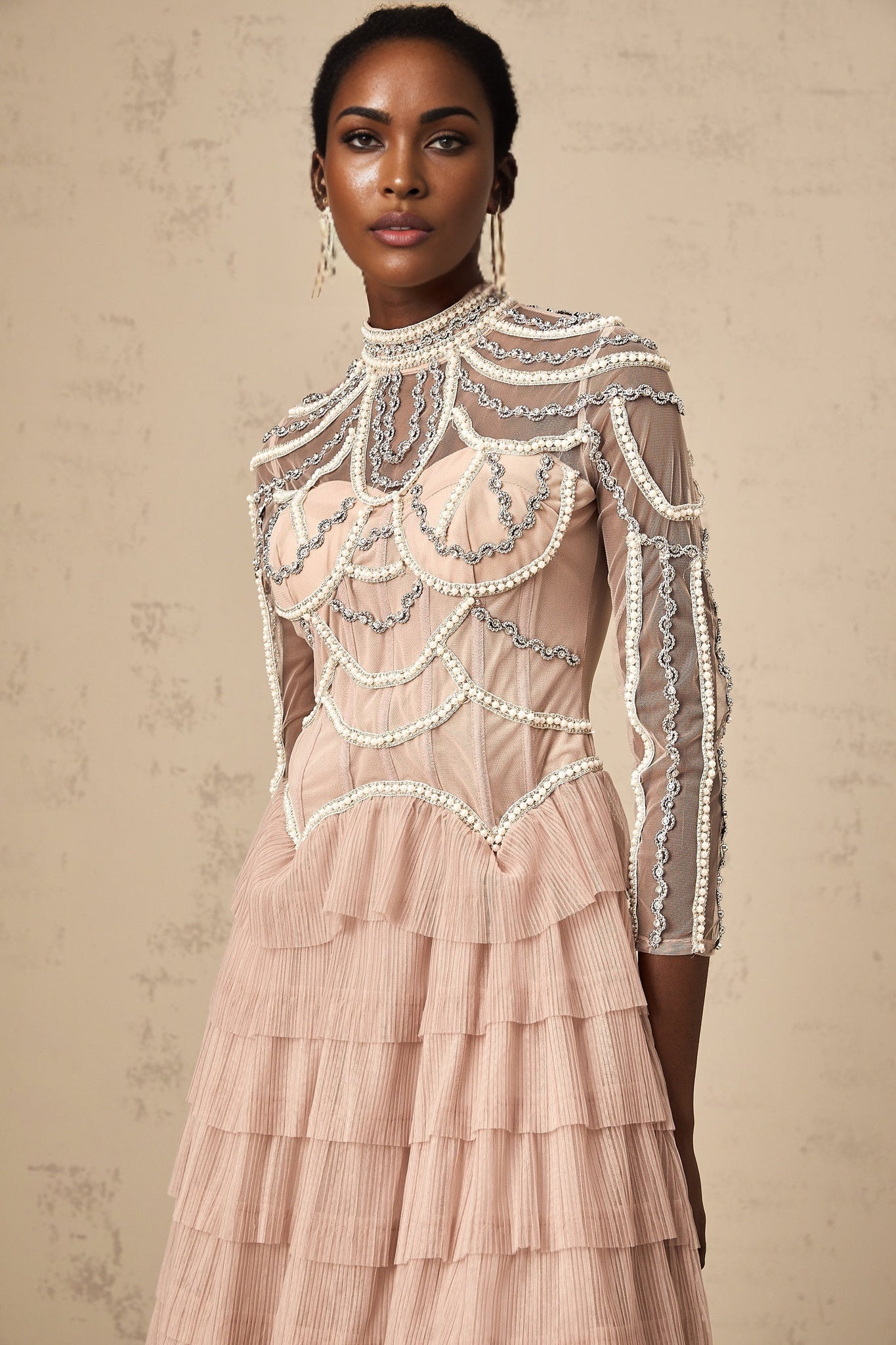 Woman wearing long pink gown with beaded details and tiered semi sheer skirt