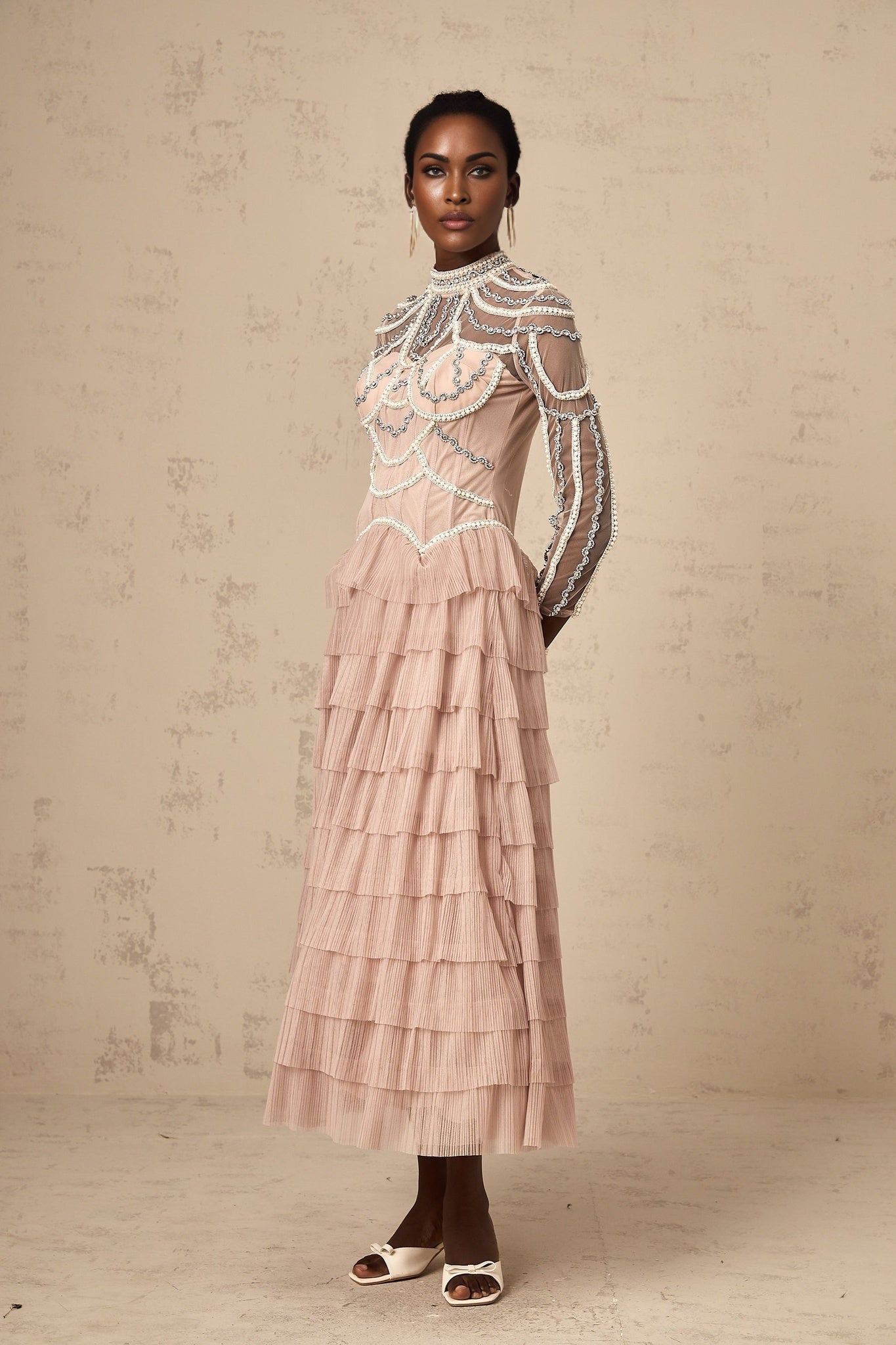 Woman wearing long pink gown with beaded details and tiered sheer skirt
