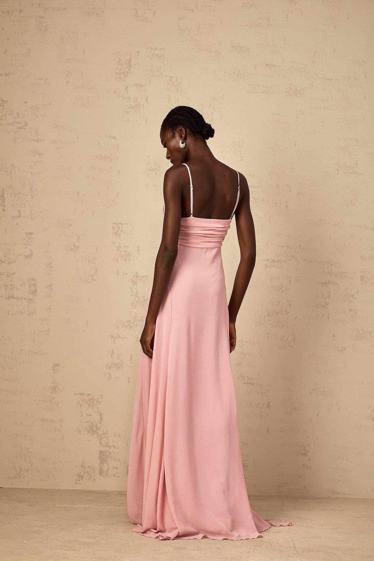 Woman wearing long pink maxi dress with 3D petal tulle details flowing skirt and sleeveless bodice