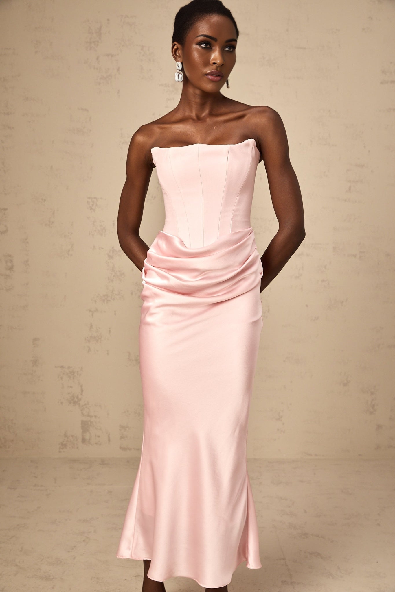 Woman wearing long pink offshoulder maxi dress with flowing skirt standing outdoors