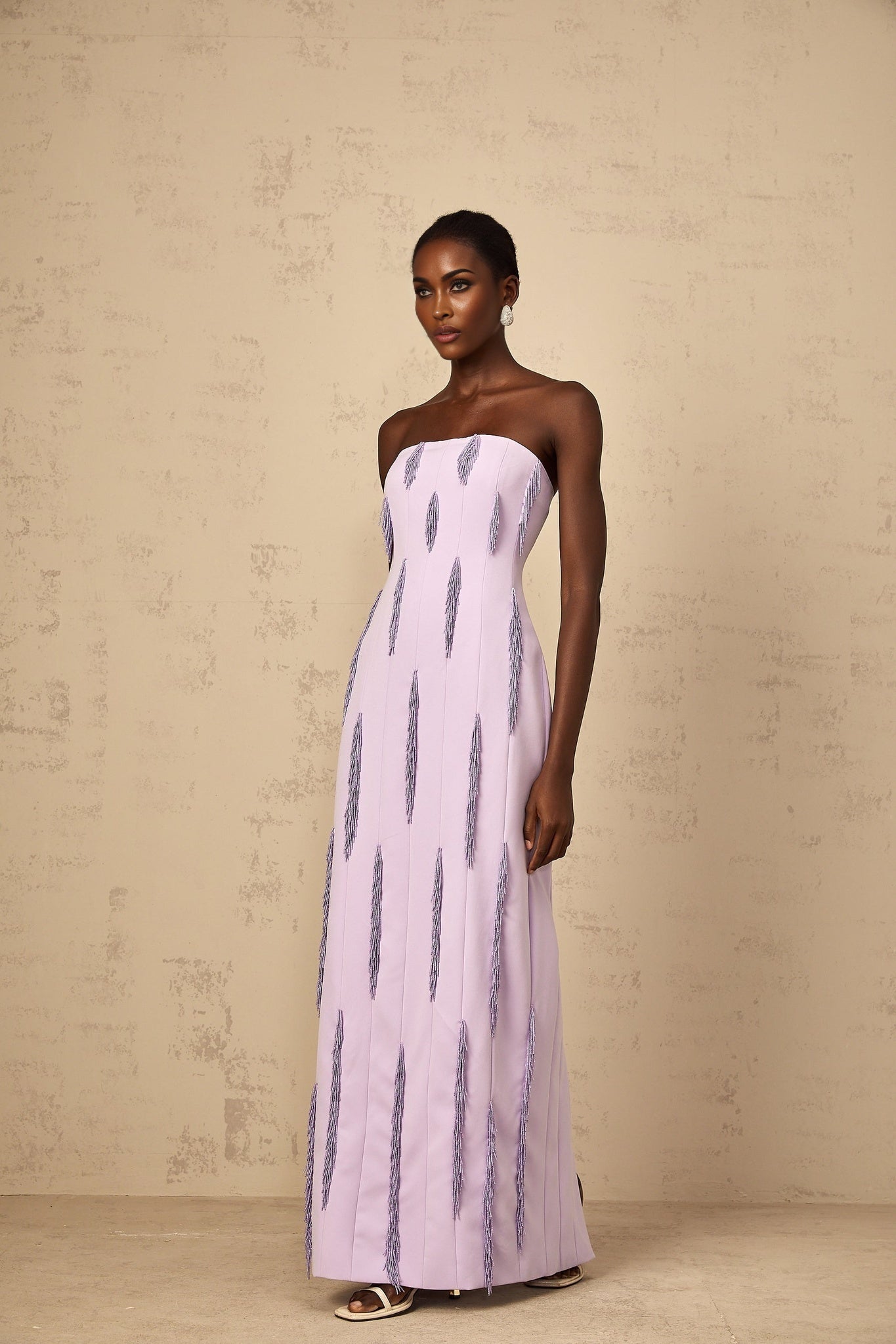Woman wearing long purple maxi dress with beaded fringe detail and sleeveless design standing in relaxed pose