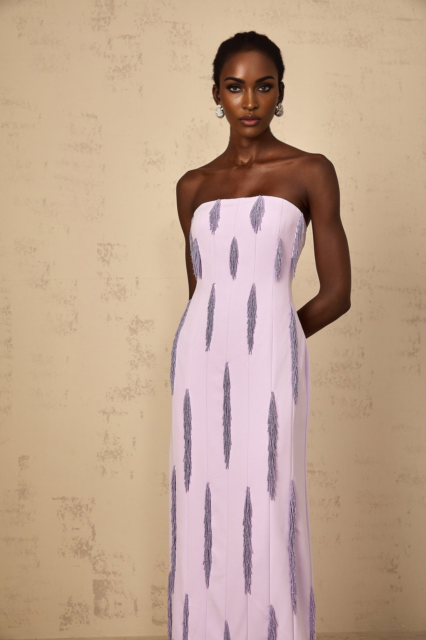 Woman wearing long purple maxi dress with beaded fringe details and thin straps